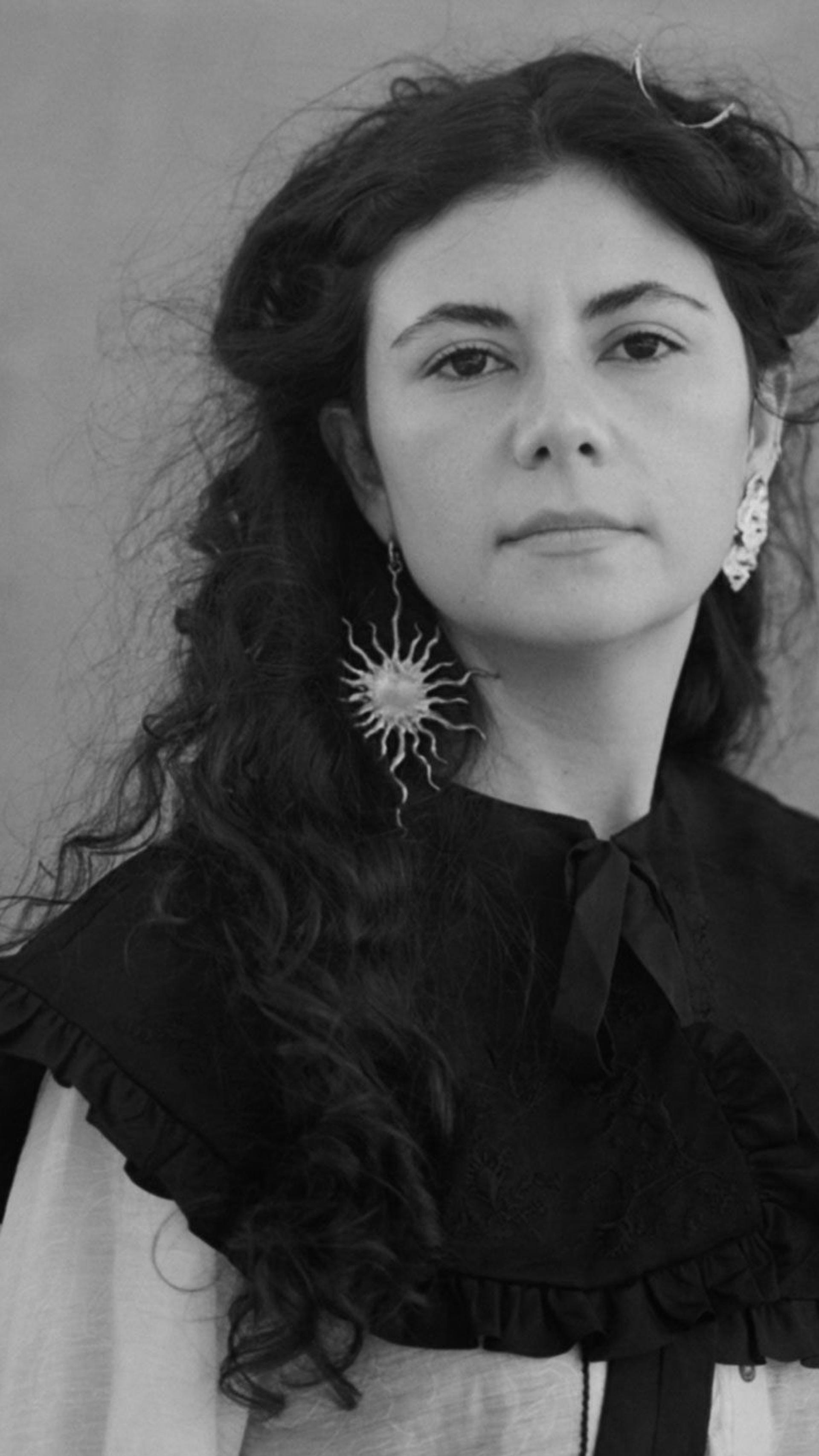 Indira Elias looking at the camera, wearing a Sun-like earring.