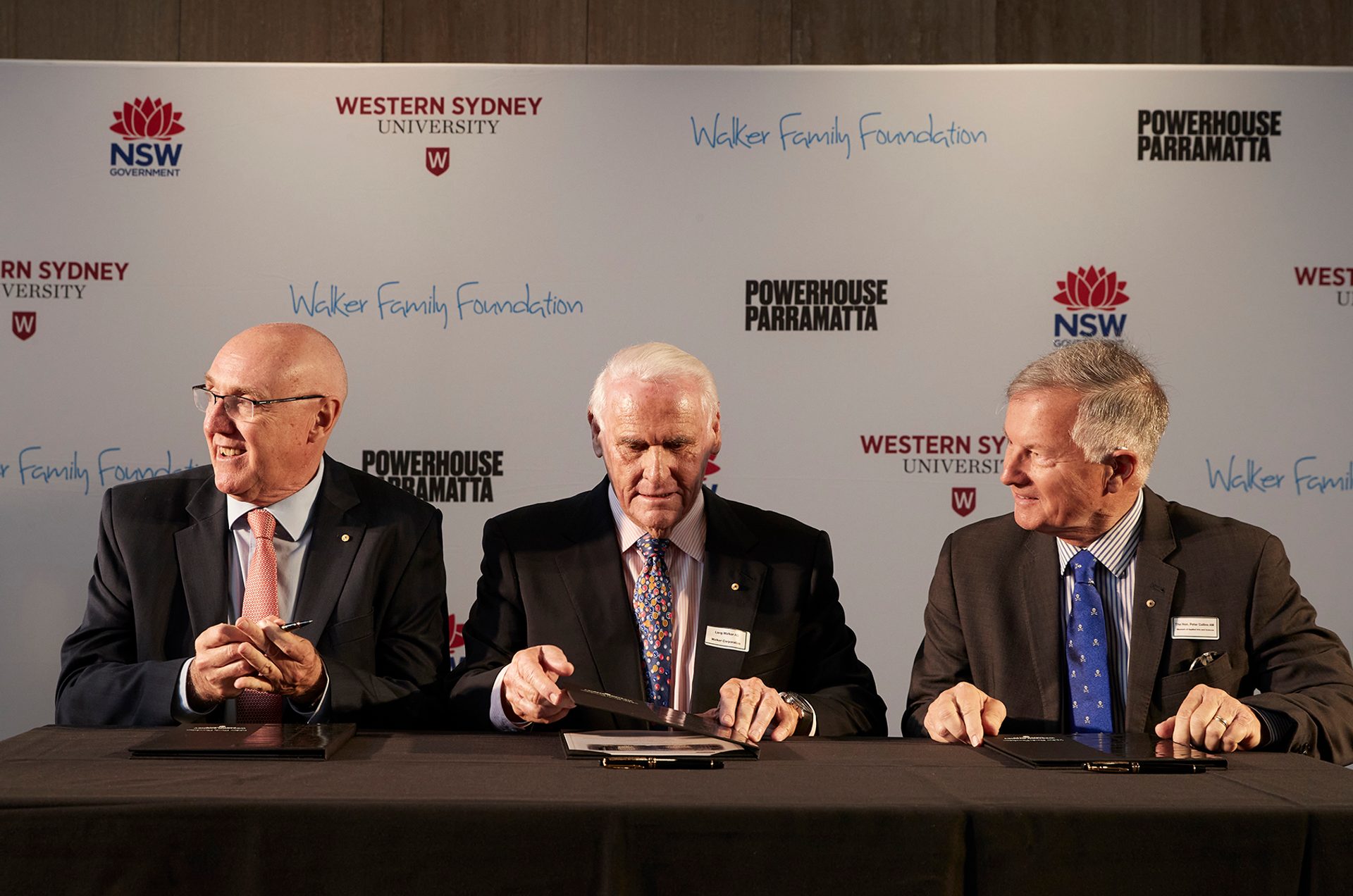 3 men in suits sitting with clipboards