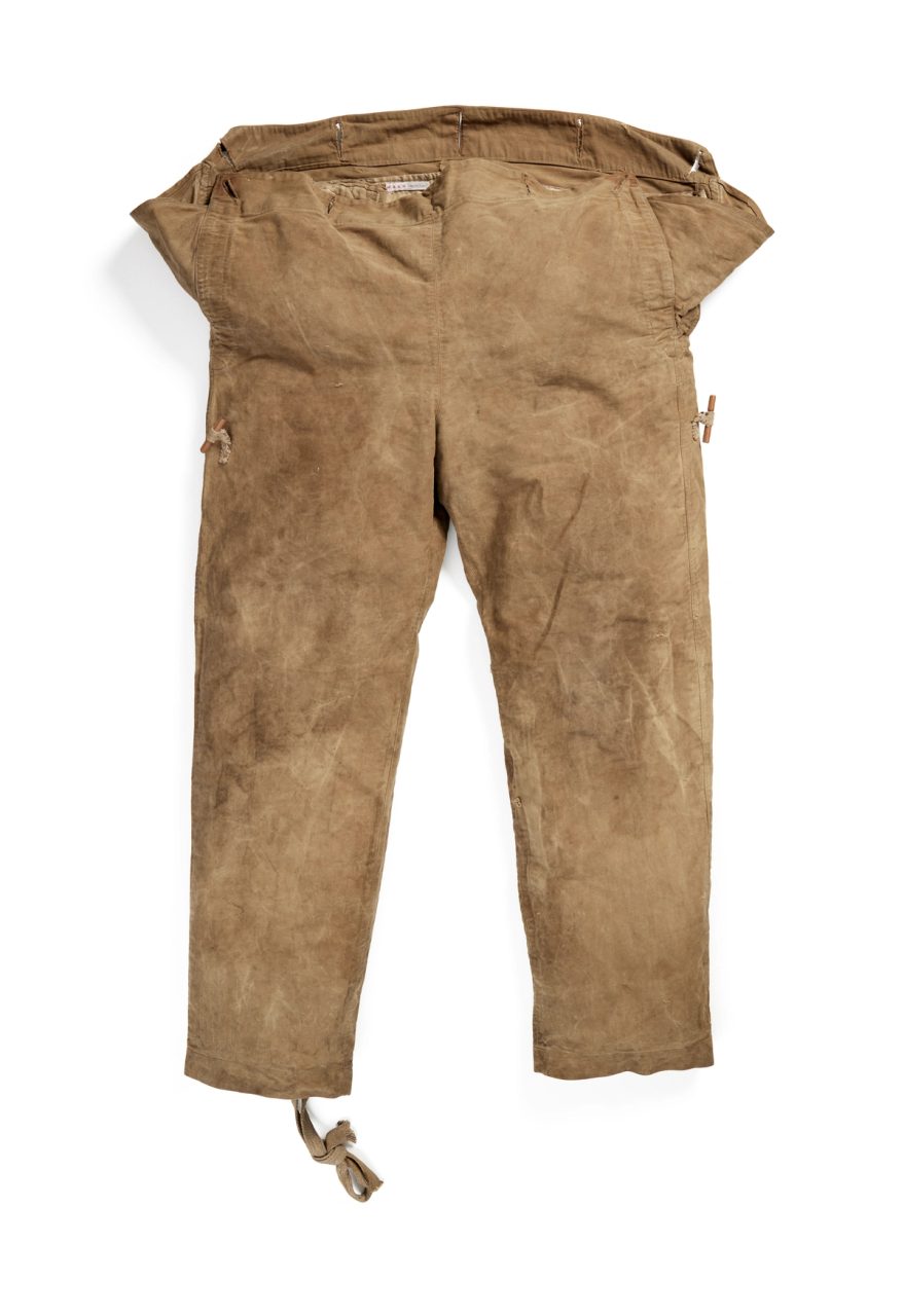 Light brown overalls, made from heavy cotton twill, large waist band designed to be buttoned to top clothes, with buttons and wood toggles.