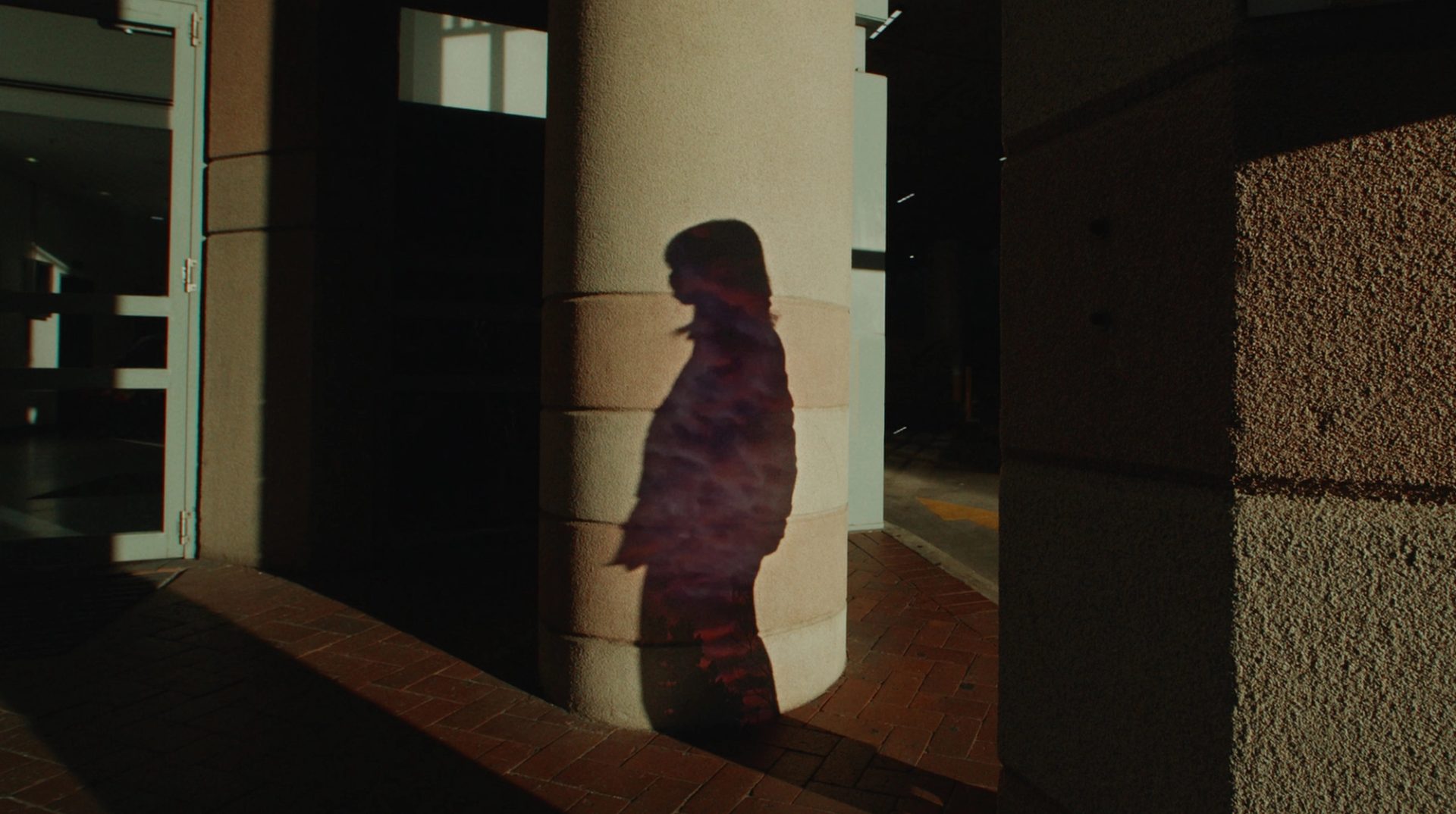 Shadowed figure on pilar with clouds atop the shadow.