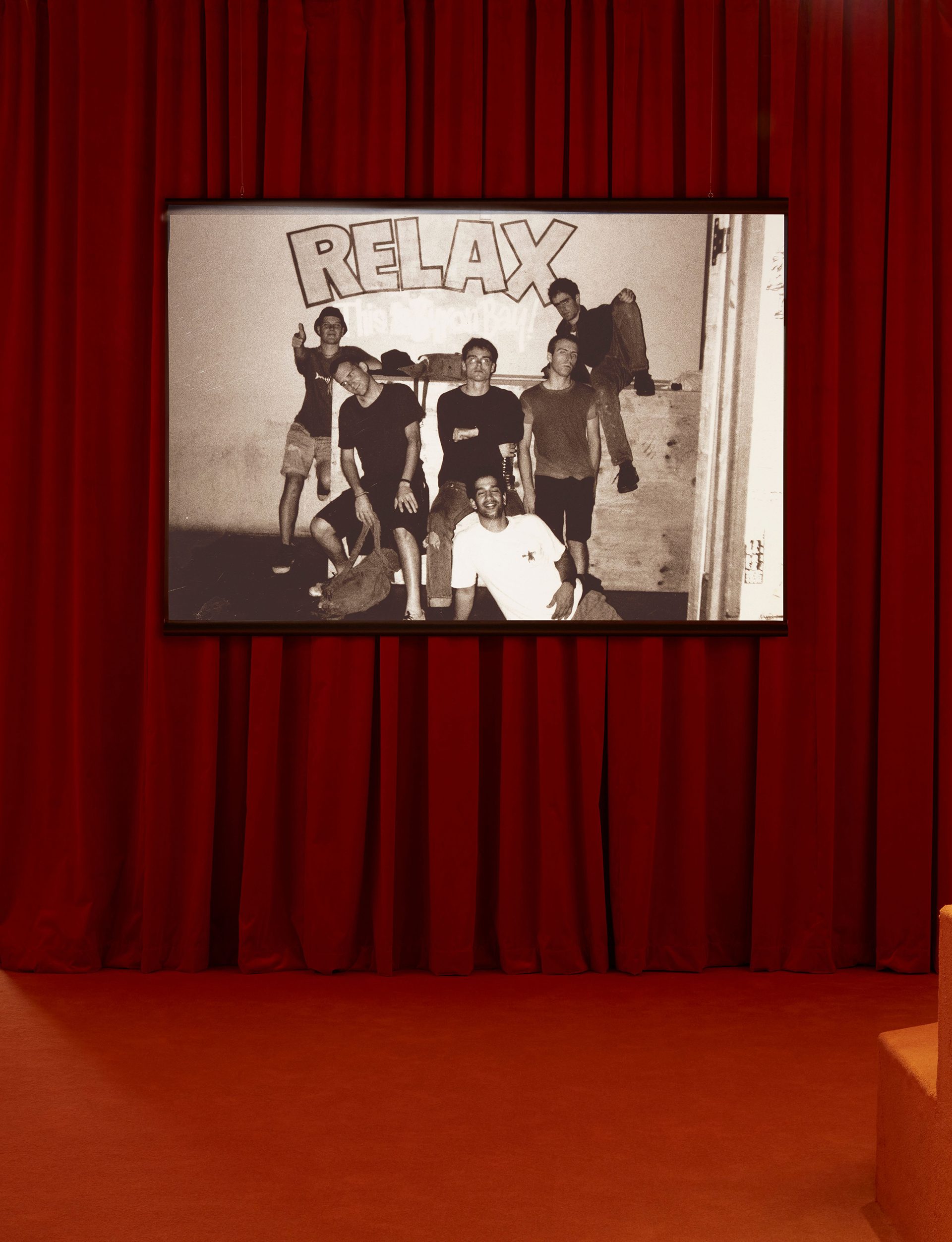 A room with red carpet and a red curtain wall with a screen hanging on it.