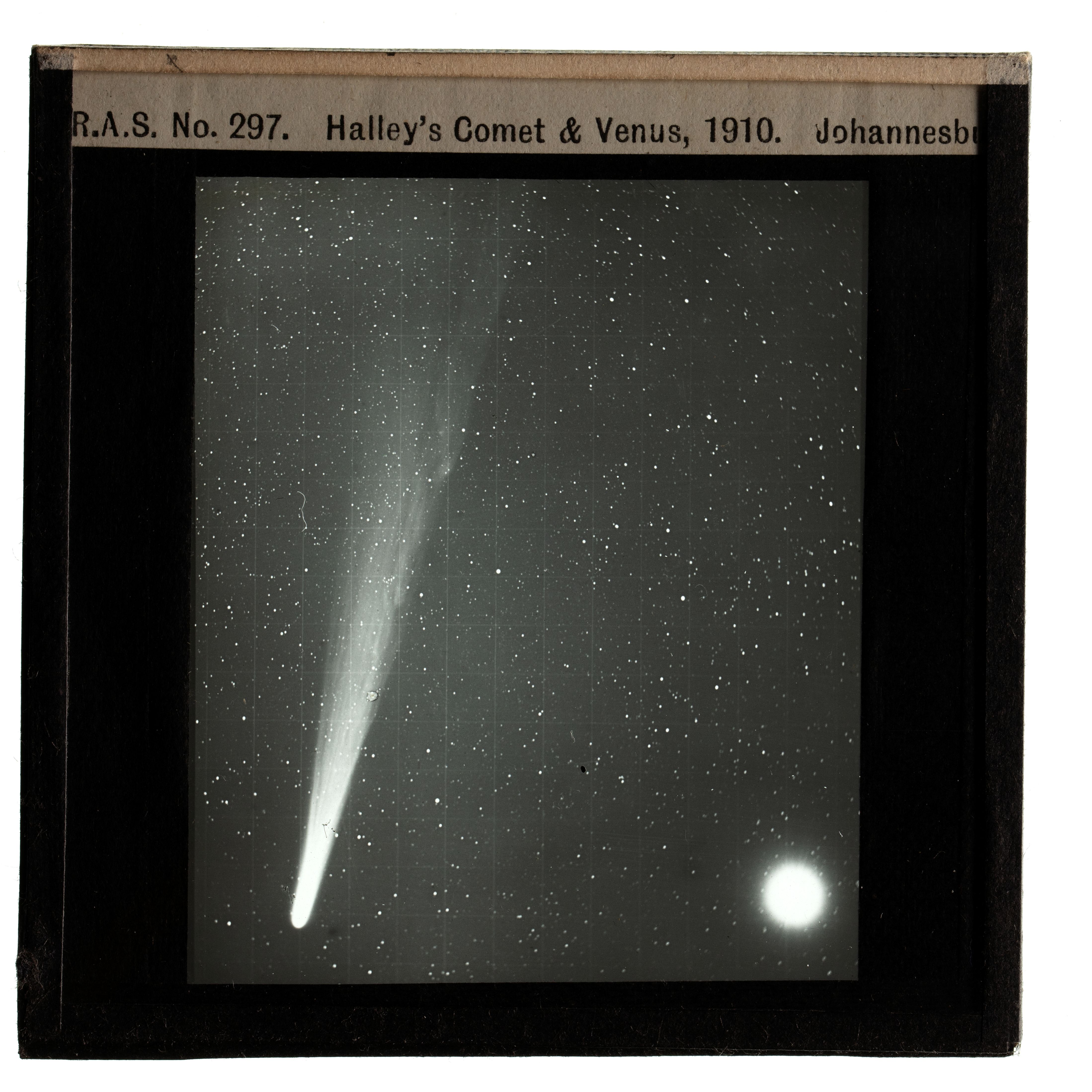 Photograph of a black framed glass plate slide depicting Halley's Comet & Venus. Written on the top of the frame is 'R.A.S. No. 297. Halley's Comet & Venus, 1910. Johannesburg'.