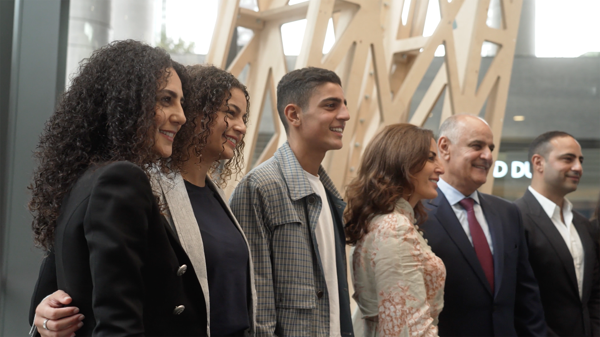 Six people stand and pose for a photo, they are smiling at the camera