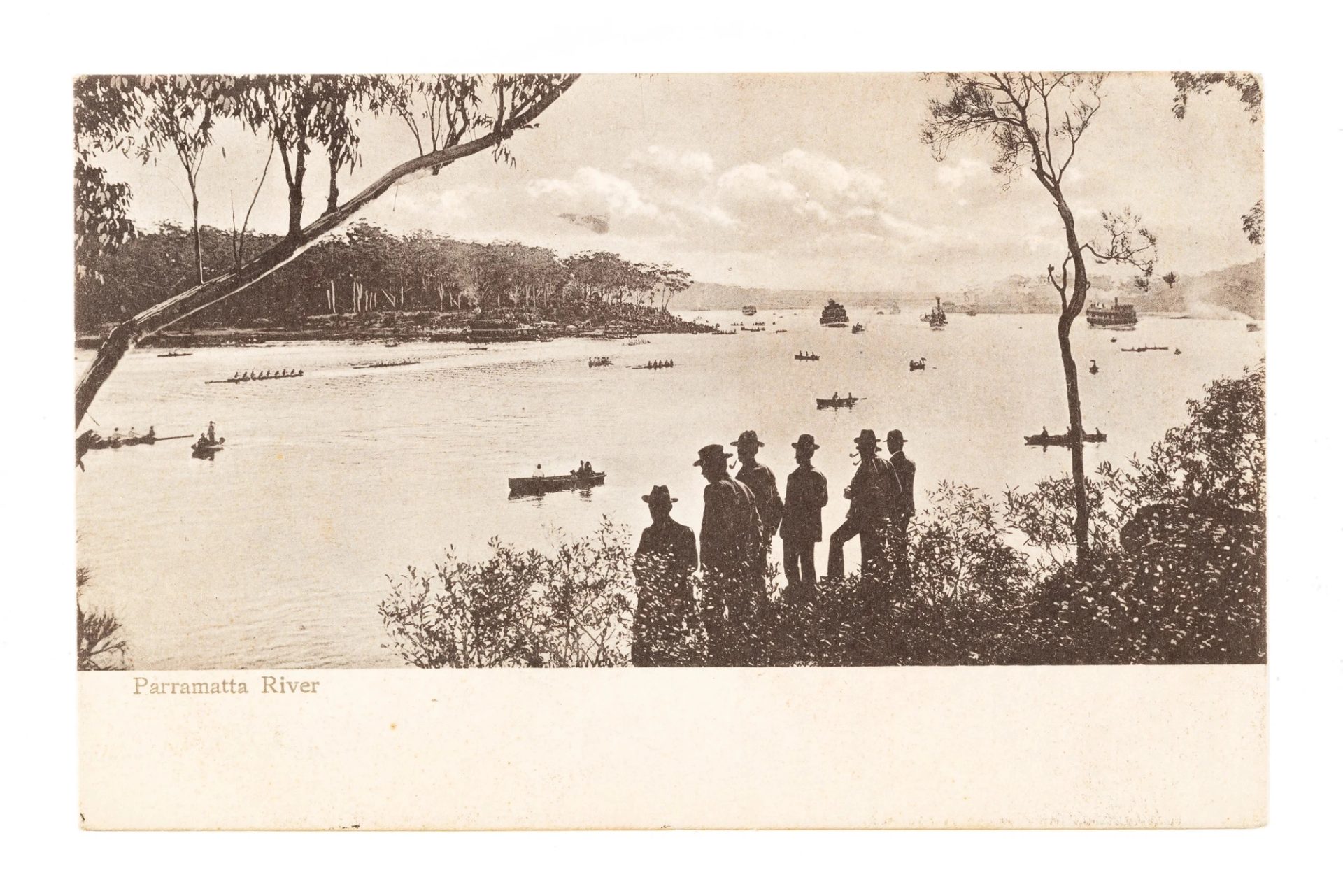 A river with its banks covered in shrubs and trees. There are boats on the water and six male figures in hats standing on the bank. Text on the left reads 'Parramatta River'.