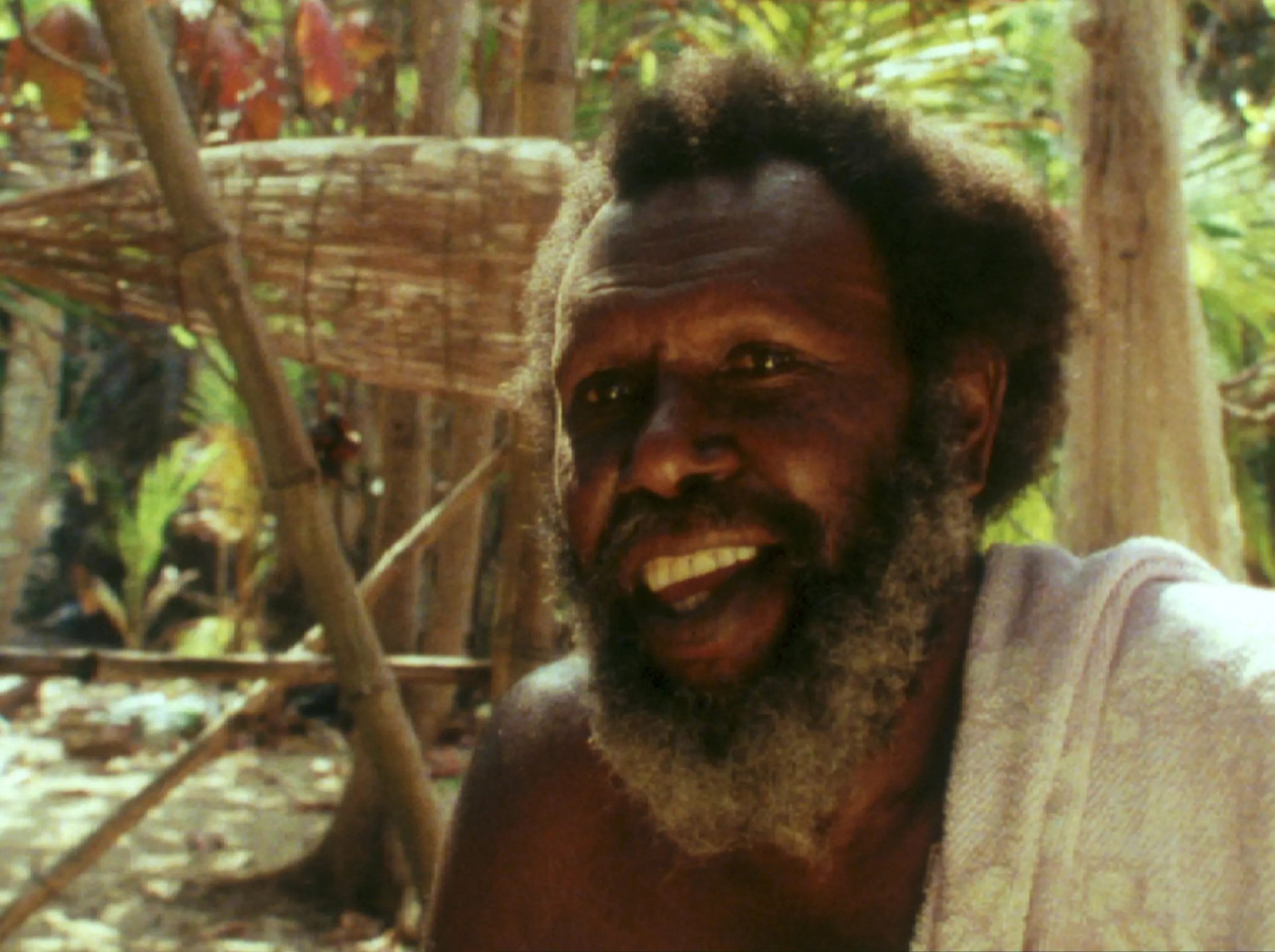 Koiki Mabo sitting within bamboo and sand backgorund.