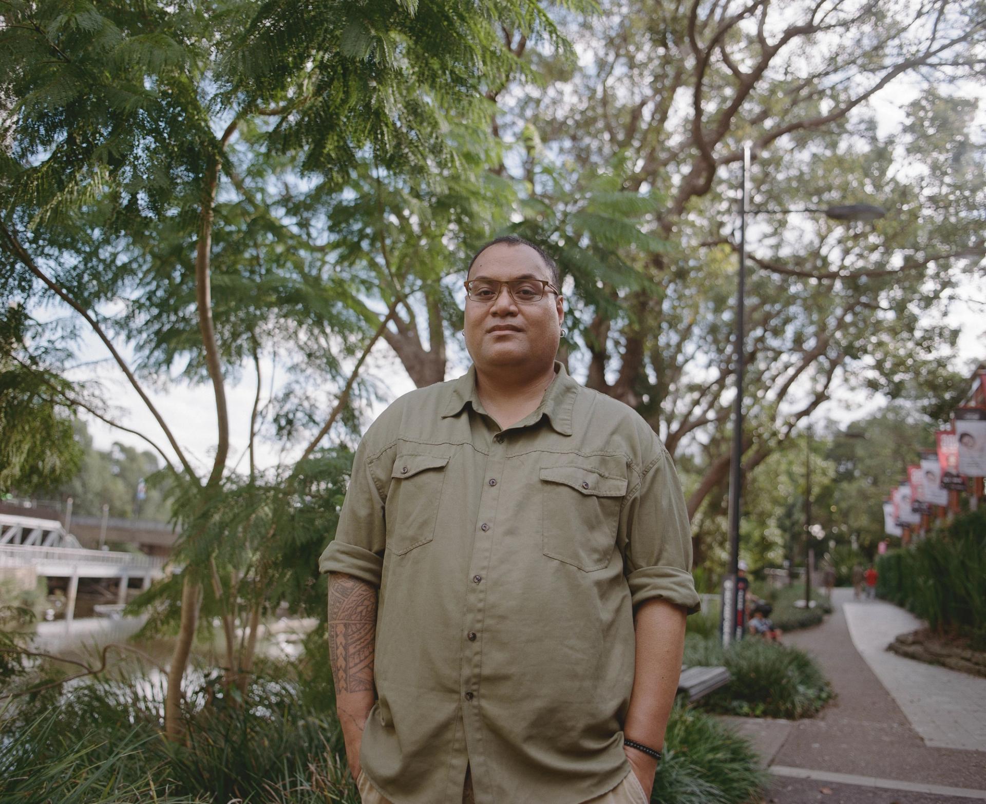 Person looks down at the camera, with hands in pockets, standing outside on a footpath.
