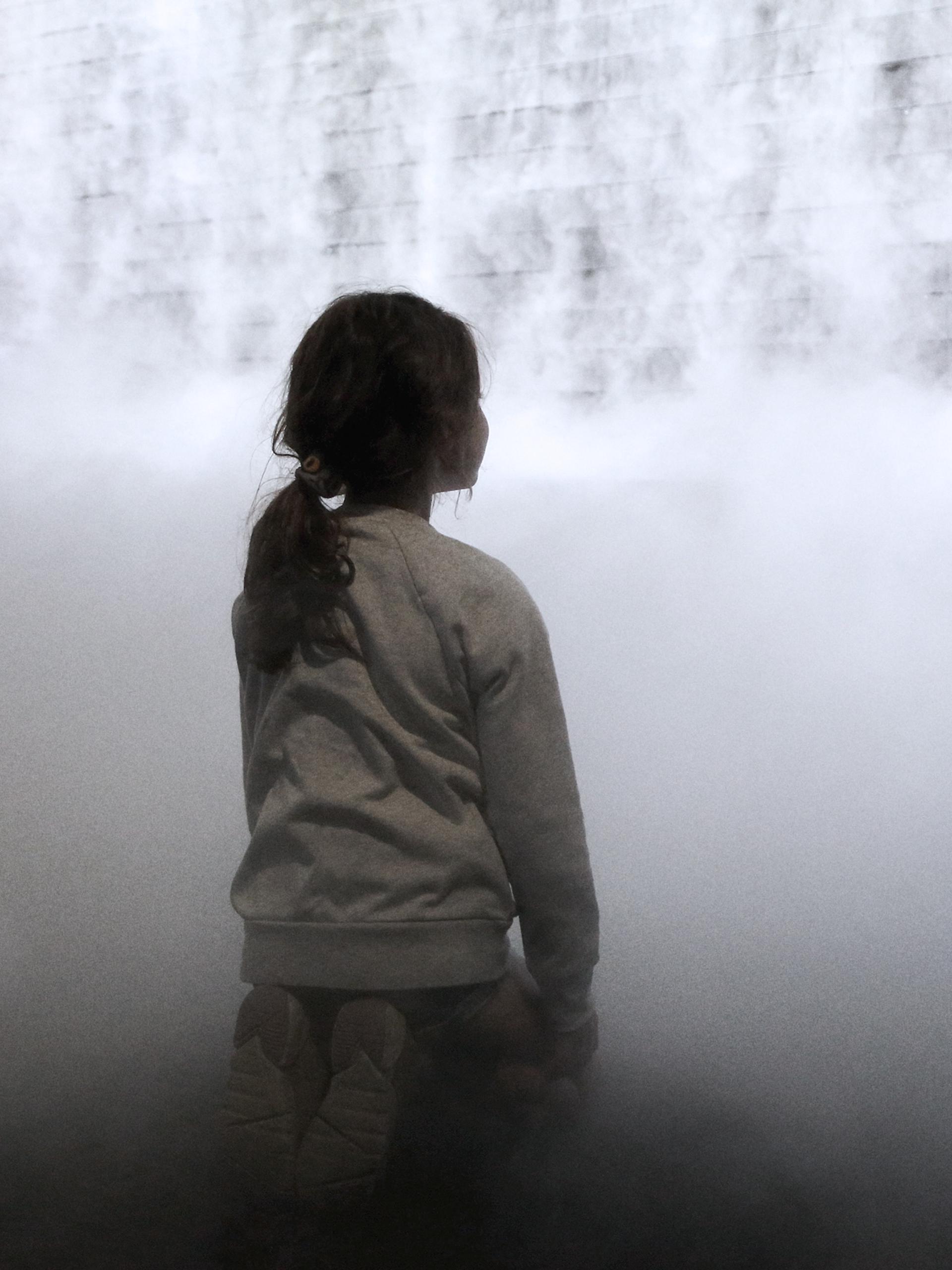 Little girl in front of cloud display, wall of smoke simulating cloud vapour