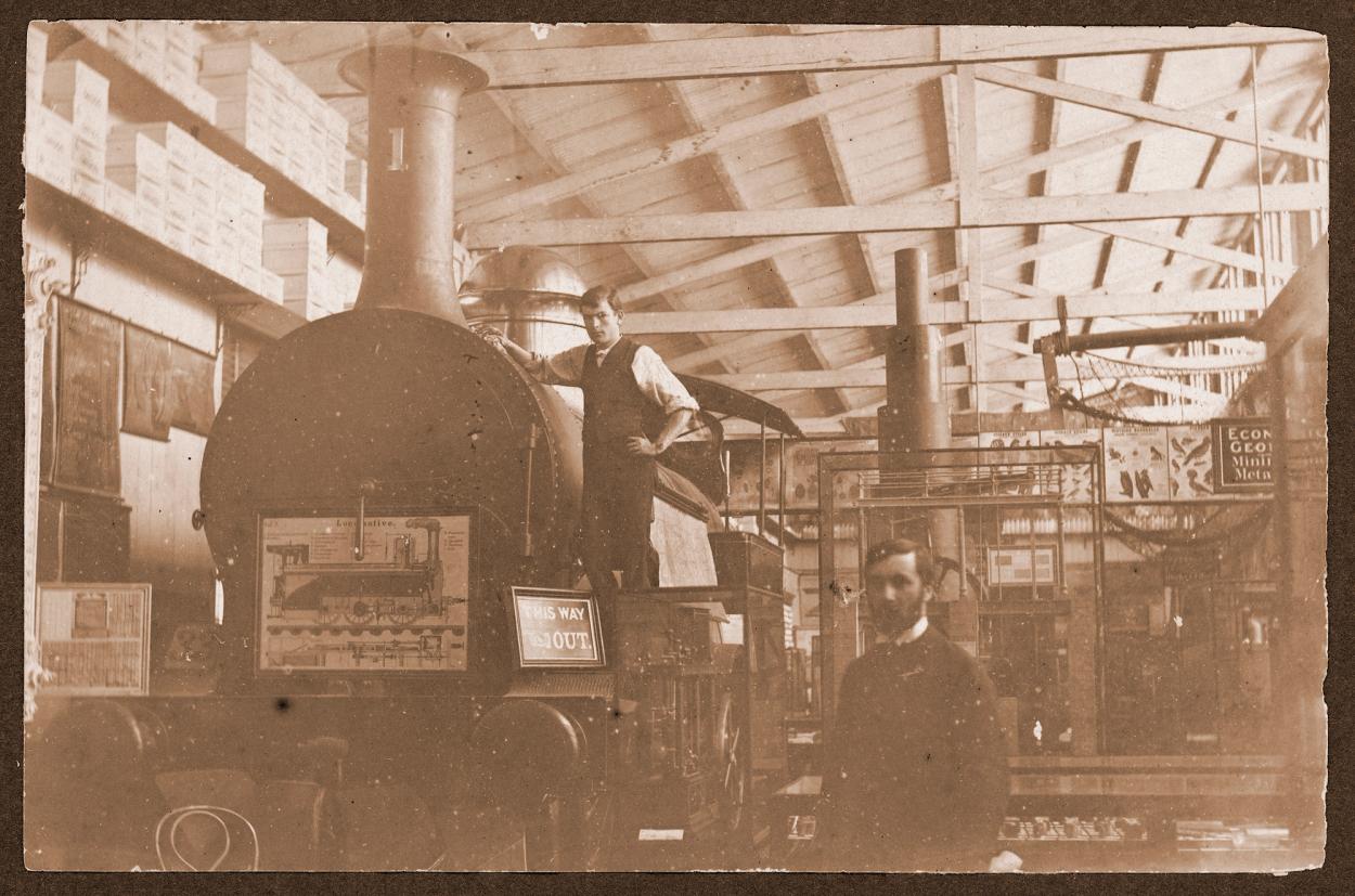 Sepia photograph of man standing on top and beside a train