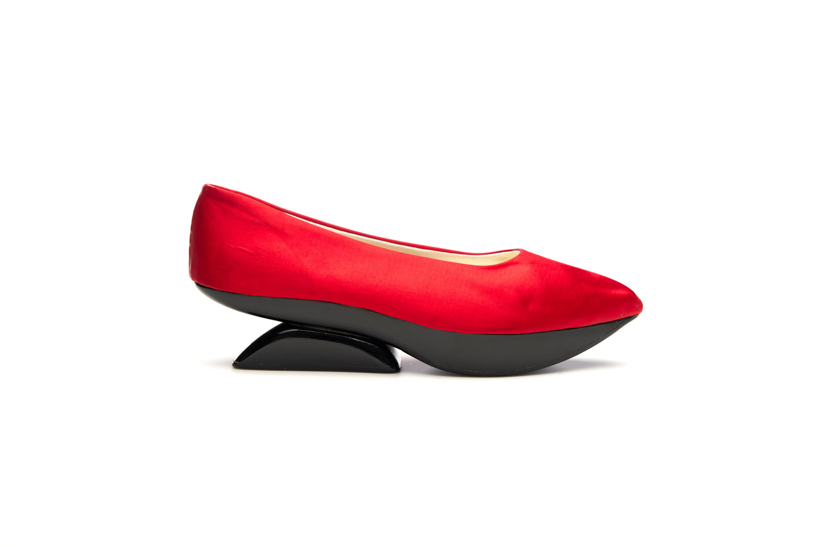 Pair of womens slip on shoes with gently pointed toe, platform sole with sculptured upturned wedge heel. Shoe consists of uppers of red silk satin in one piece.