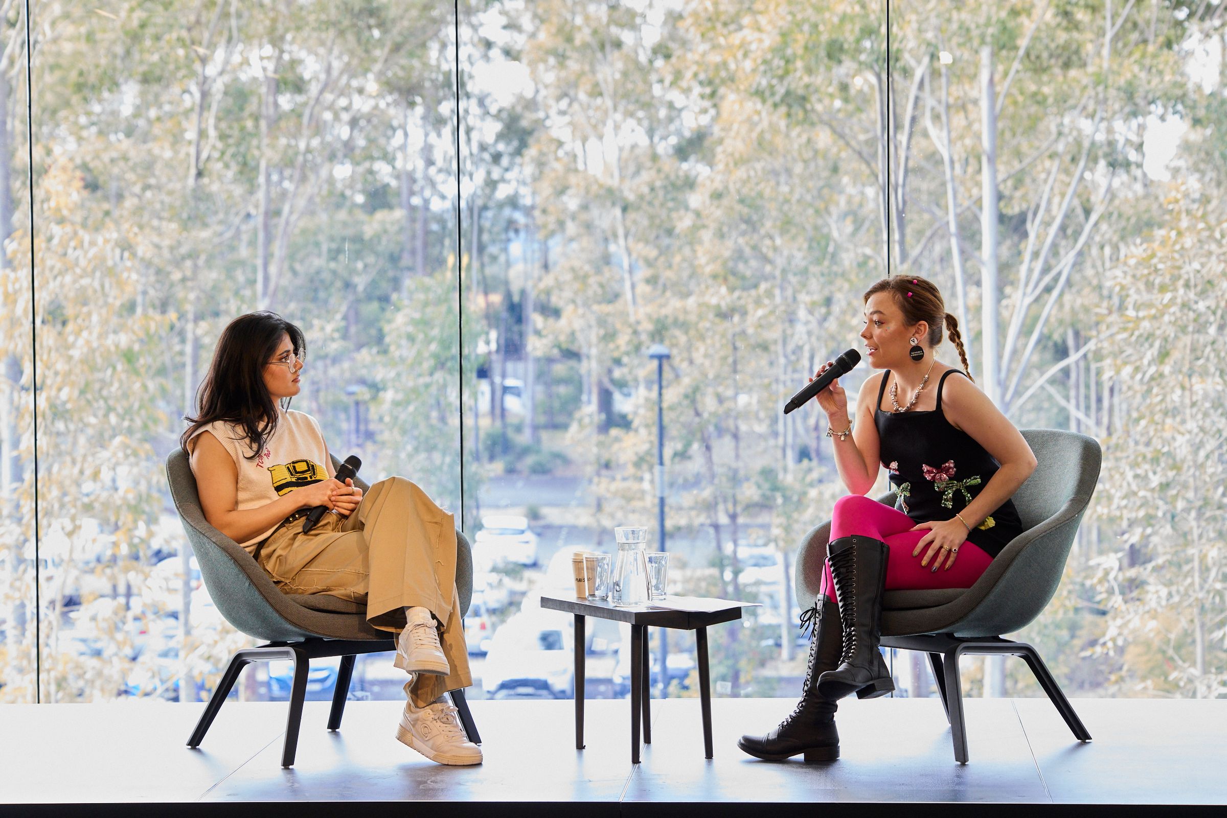 Guests Ayesha Madon (left) and Chloe Hayden (right), seated on a stage during a talk.