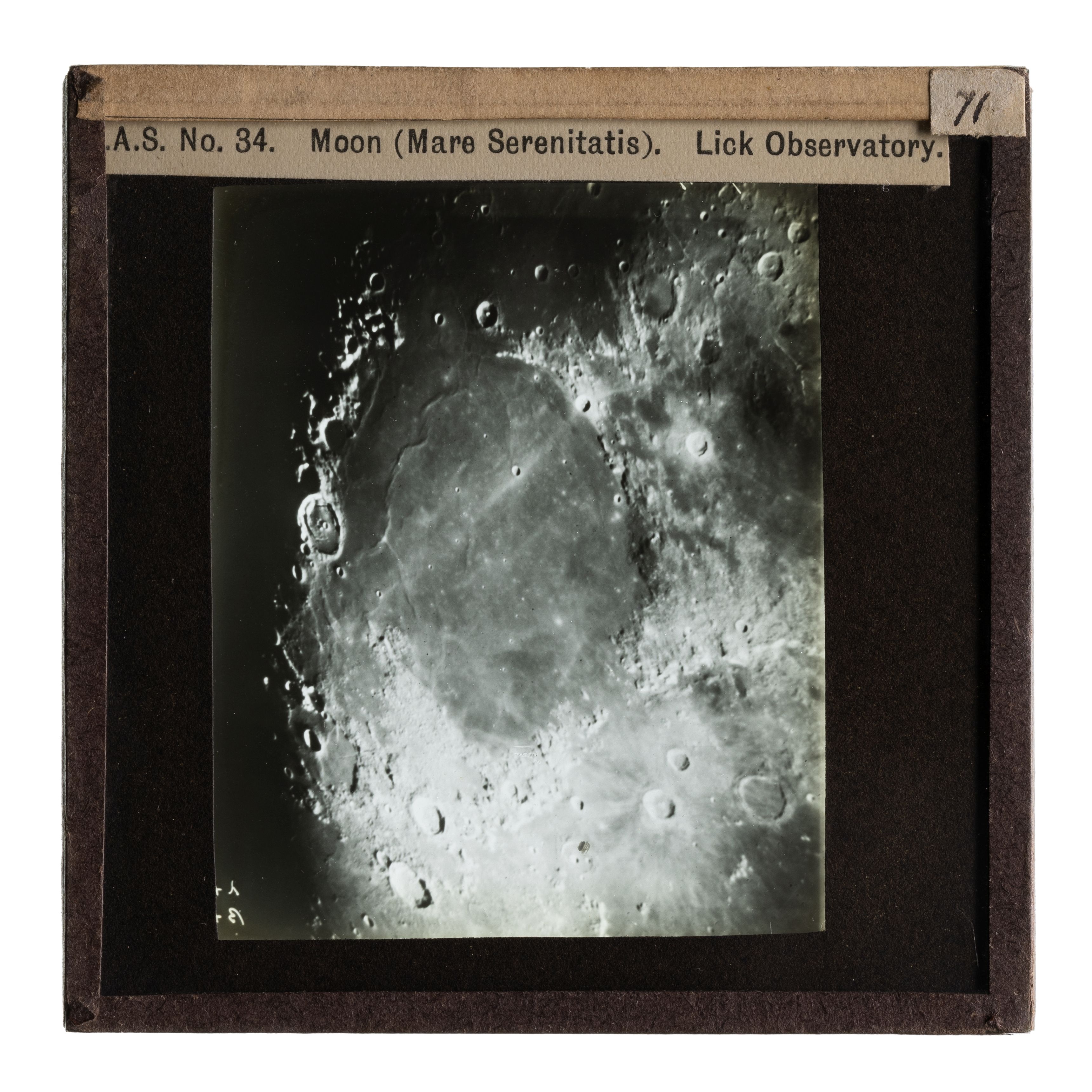Photograph of a black and brown glass plate slide with an image of 'Moon (Mare Serenitatis) Lick Observat.'