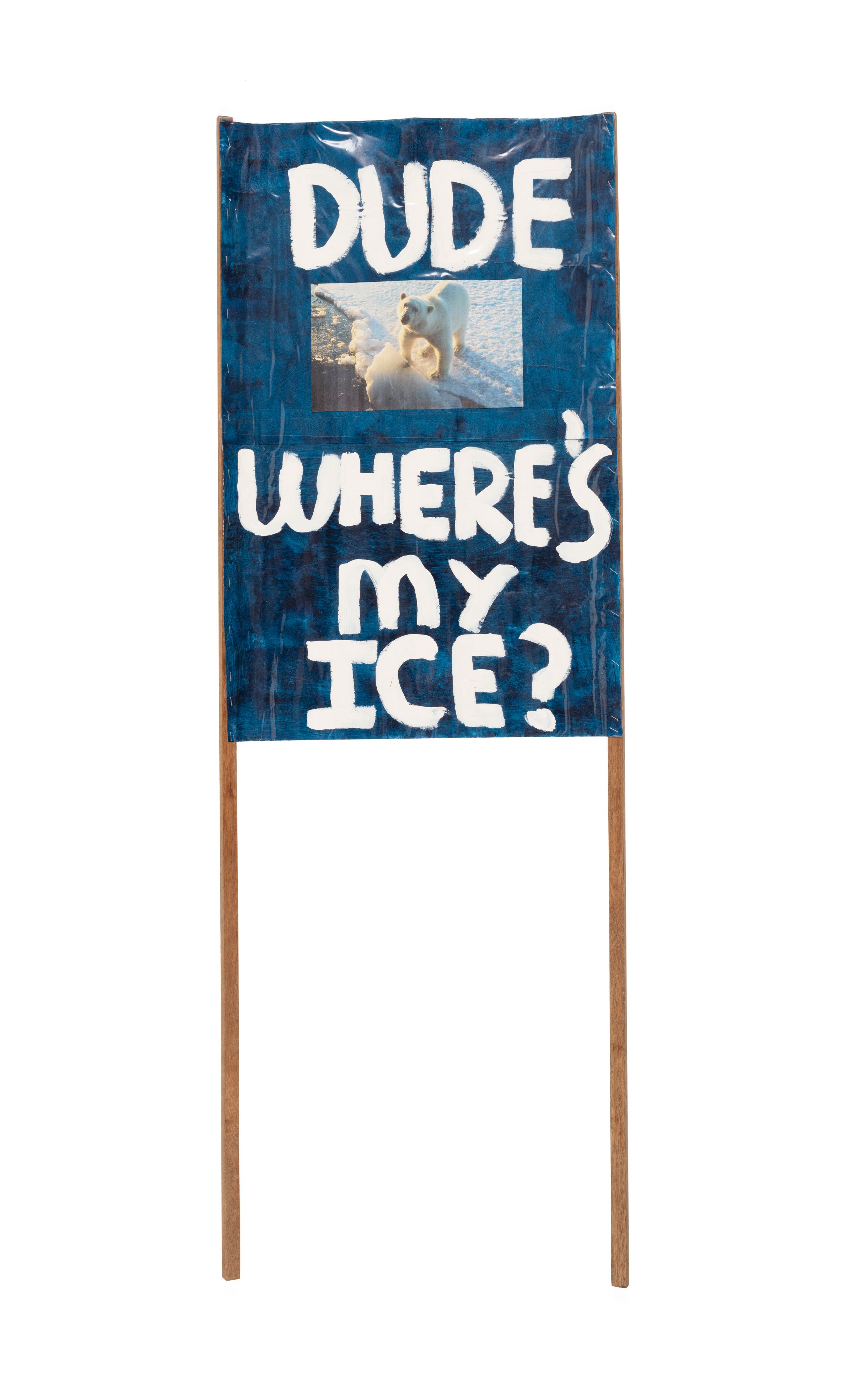 A dark blue placard with a photograph of a polar bear. The words 'Dude Where's My Ice' are painted in white paint.