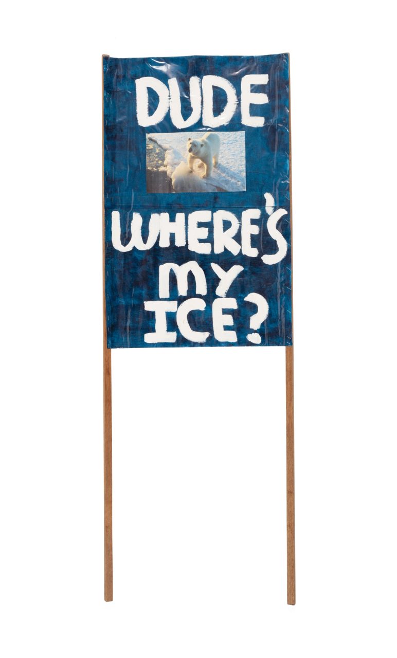 A dark blue placard with a photograph of a polar bear. The words 'Dude Where's My Ice' are painted in white paint.