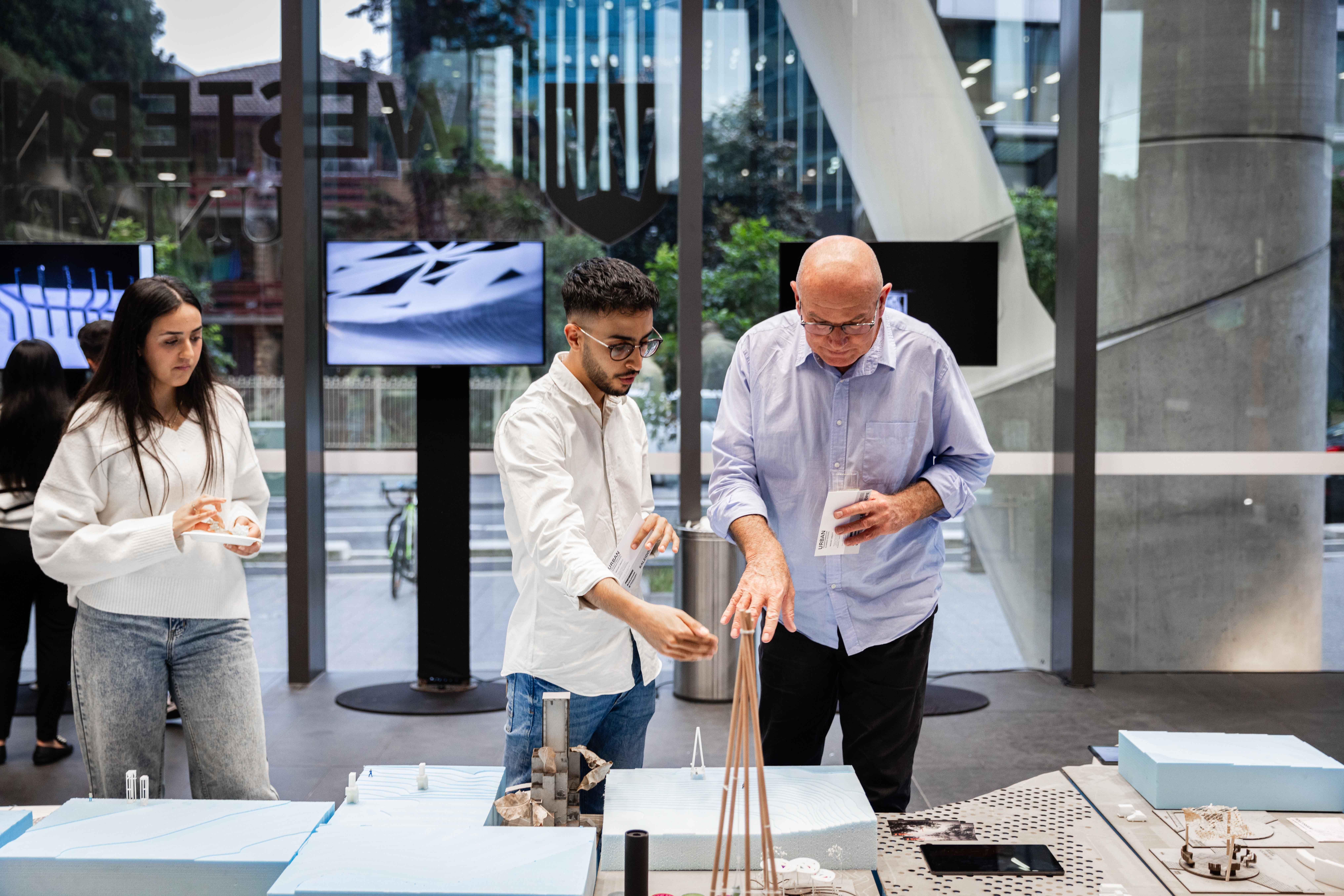 Figures standing and discussing architectural models.
