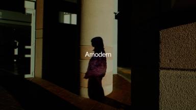 'Amodern' sits above a shadow of a figure amongst pillars of a building