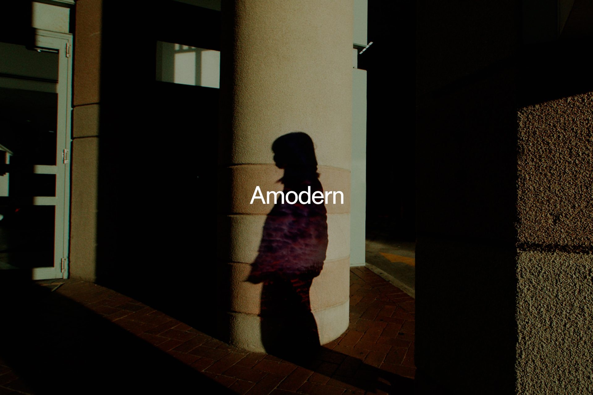 'Amodern' sits above a shadow of a figure amongst pillars of a building