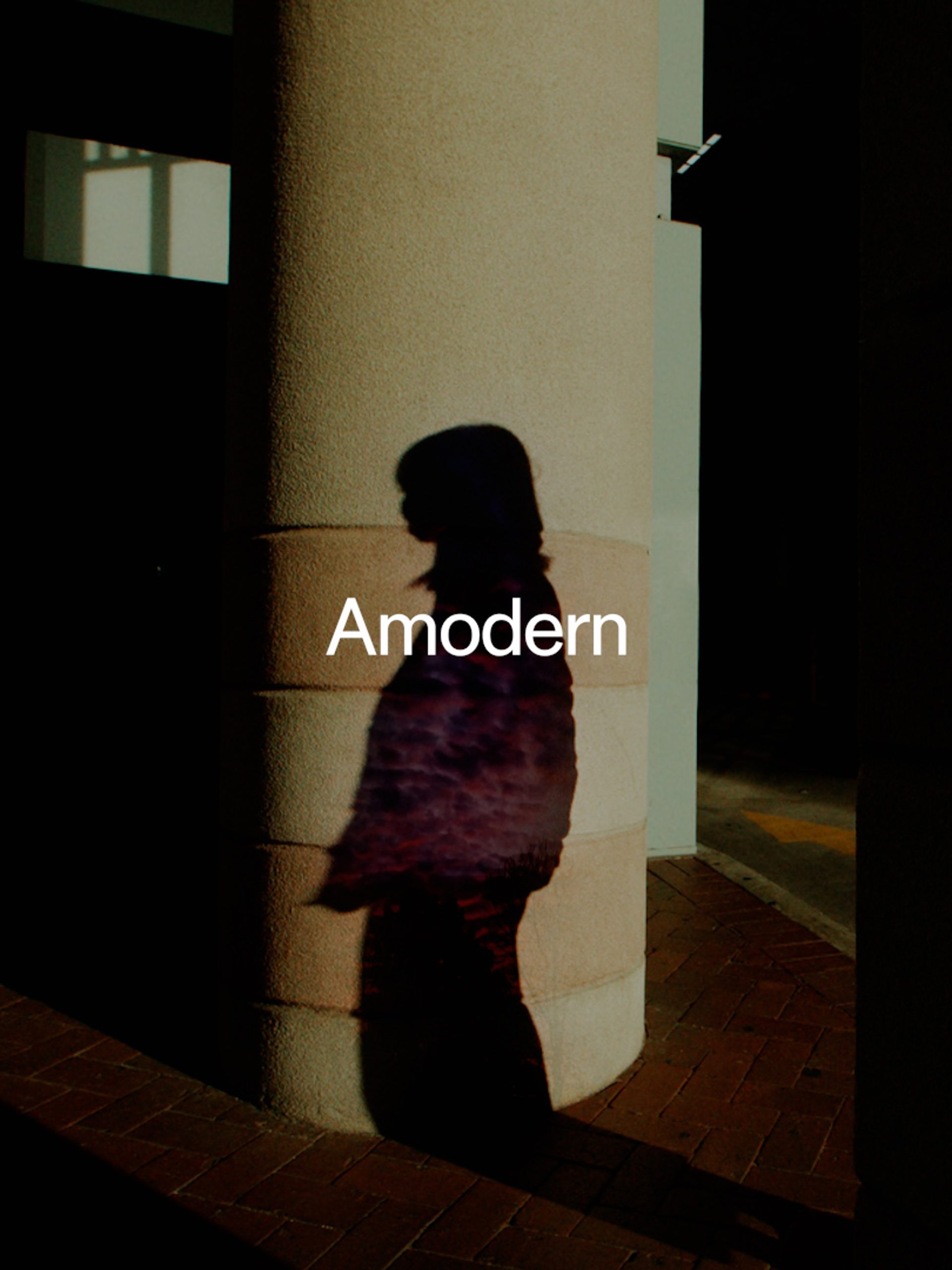 'Amodern' sits above a shadow of a figure amongst pillars of a building