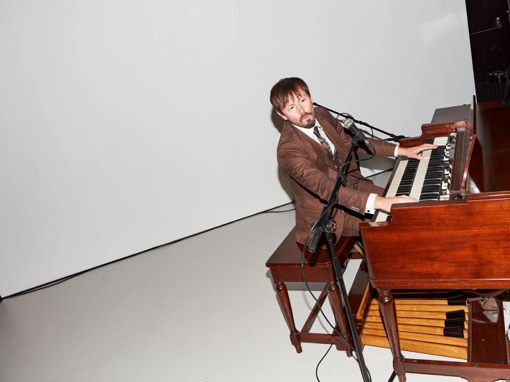 Man playing a Hammond electric organ on a white stage.
