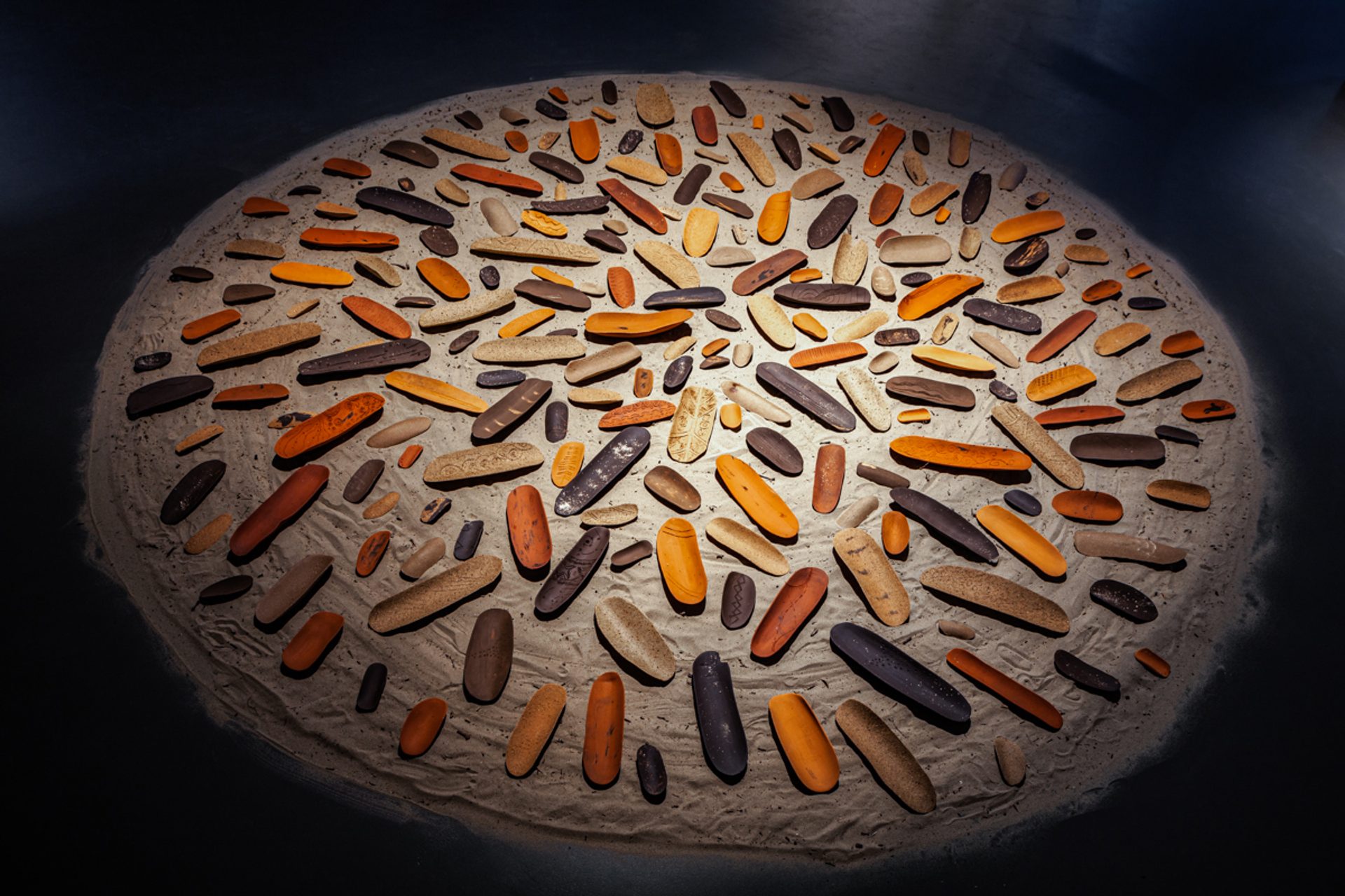 Coolamons laid out on a round circle of sand.