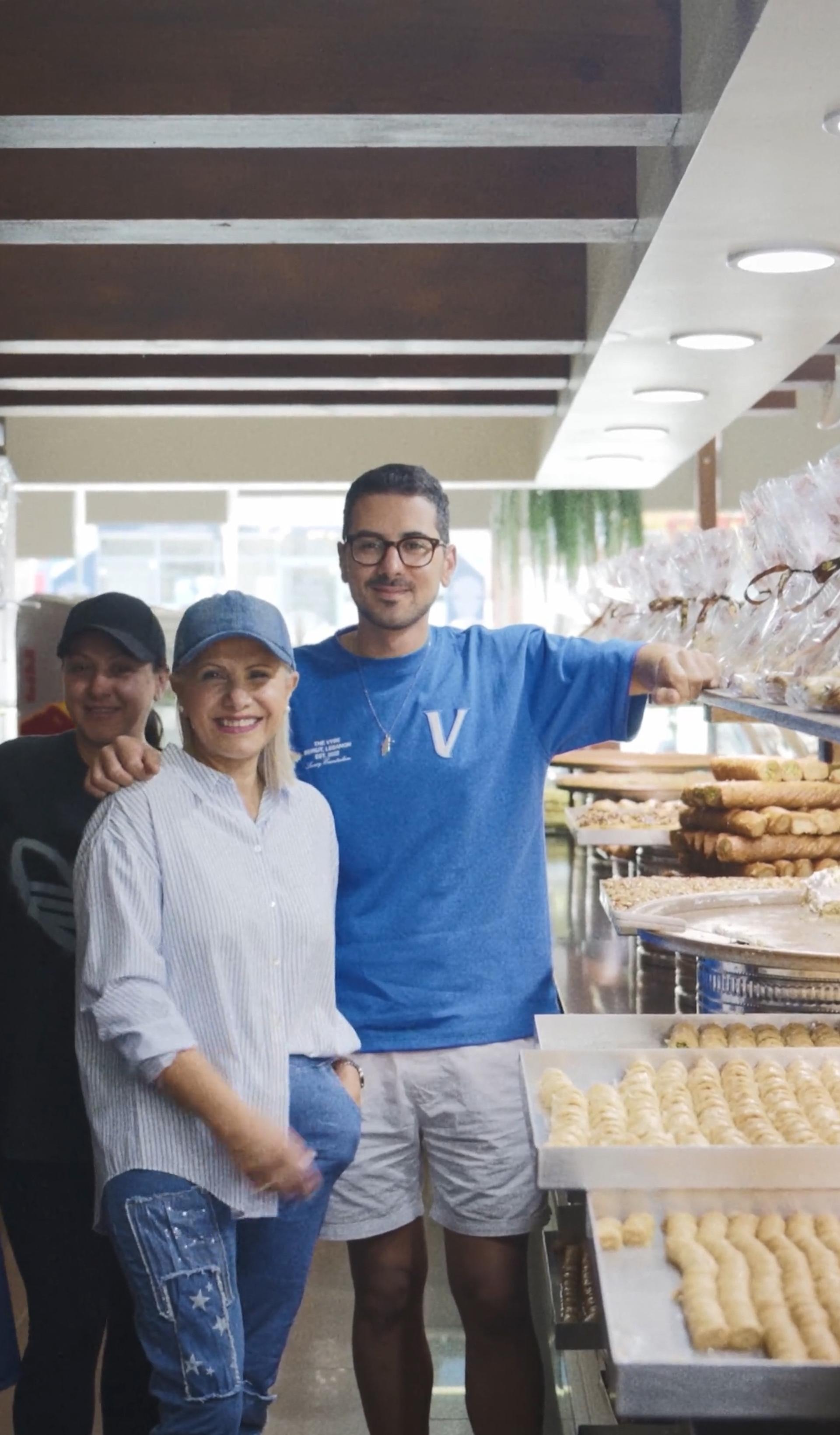 5 people standing and smiling behind a sweets display.
