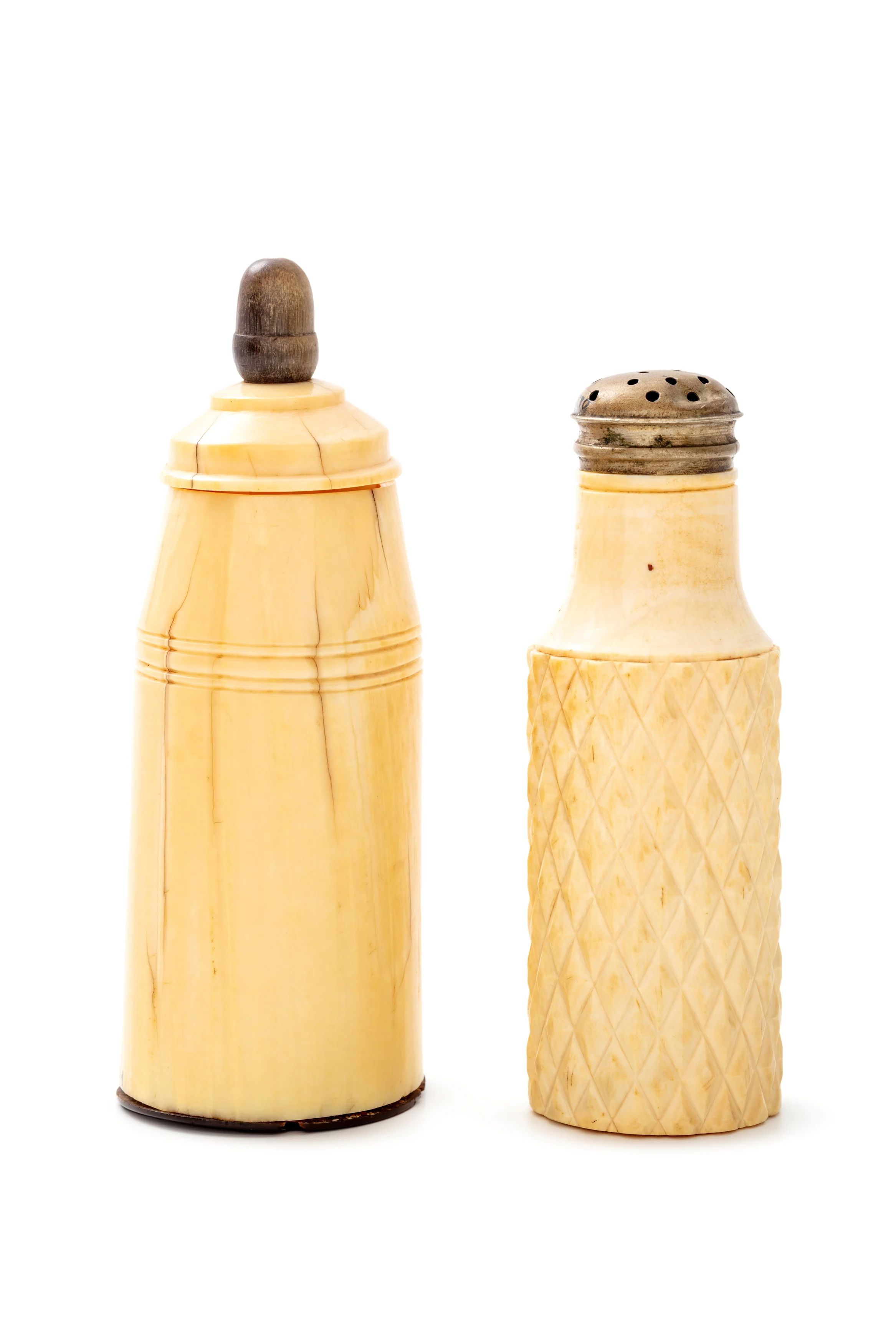 Two old bone-coloured bottles, the left one with a stopper and the other with a metal perforated lid.