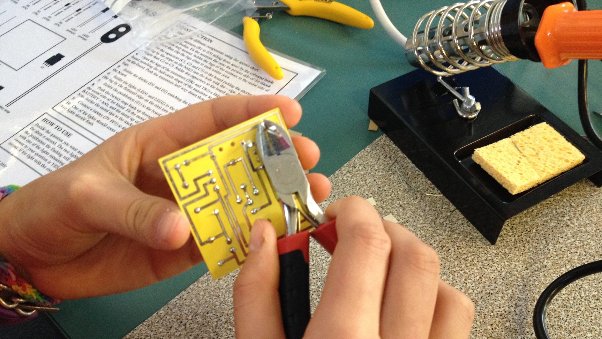 A child’s hands assemble a circuit with a light bulb on a snap-together electronic kit, showcasing a hands-on learning moment.