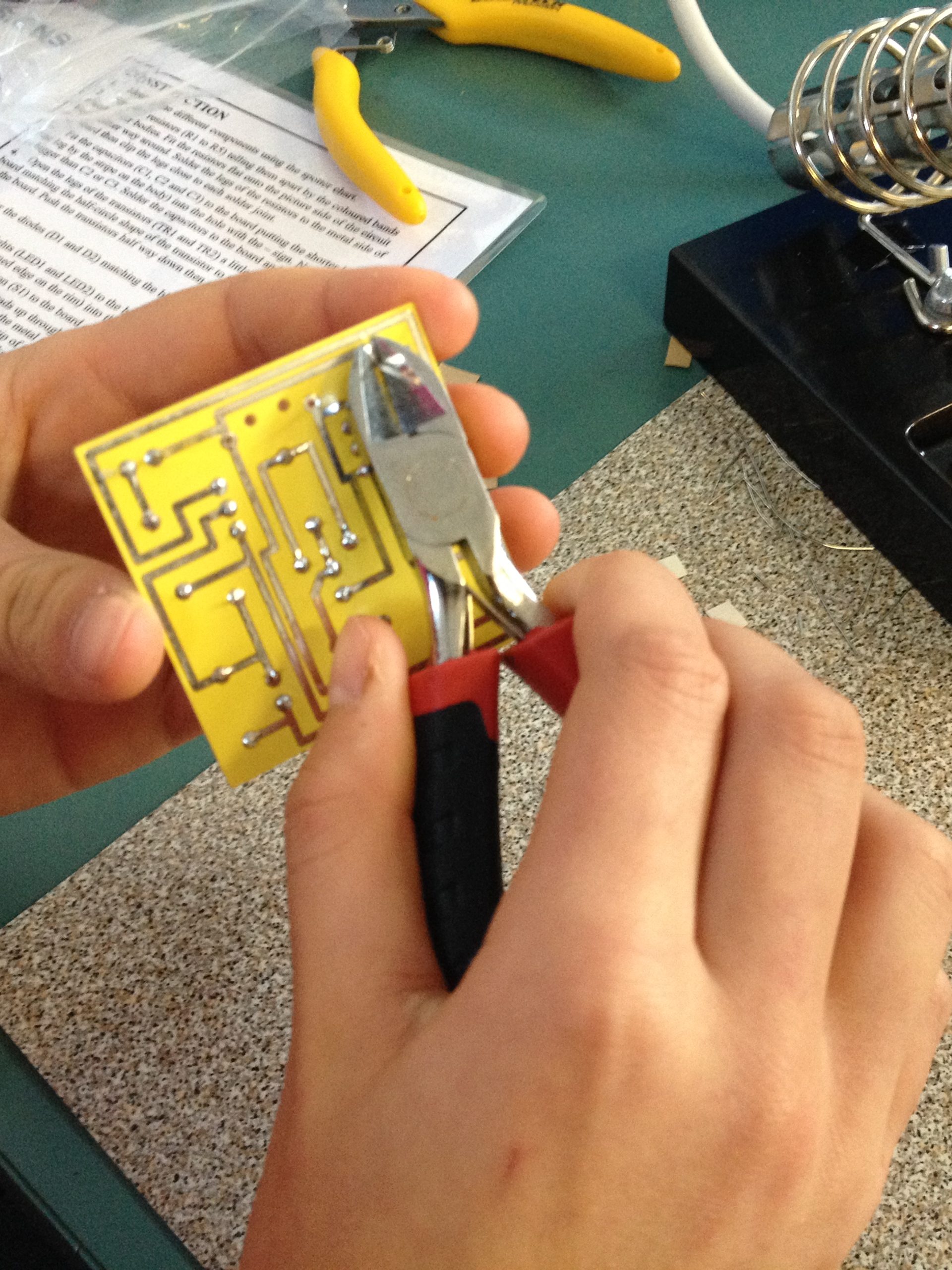 A child’s hands assemble a circuit with a light bulb on a snap-together electronic kit, showcasing a hands-on learning moment.