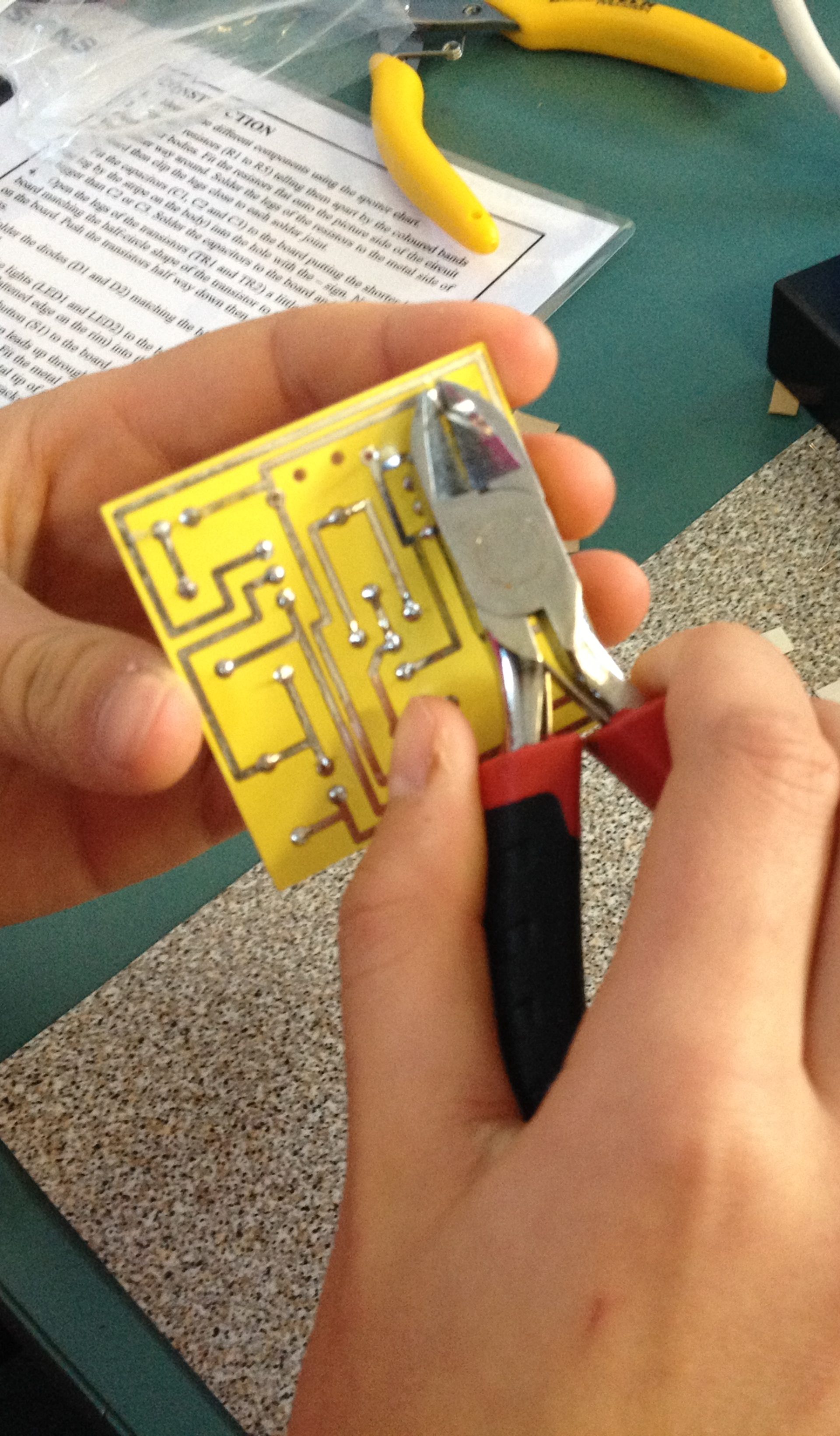 A child’s hands assemble a circuit with a light bulb on a snap-together electronic kit, showcasing a hands-on learning moment.