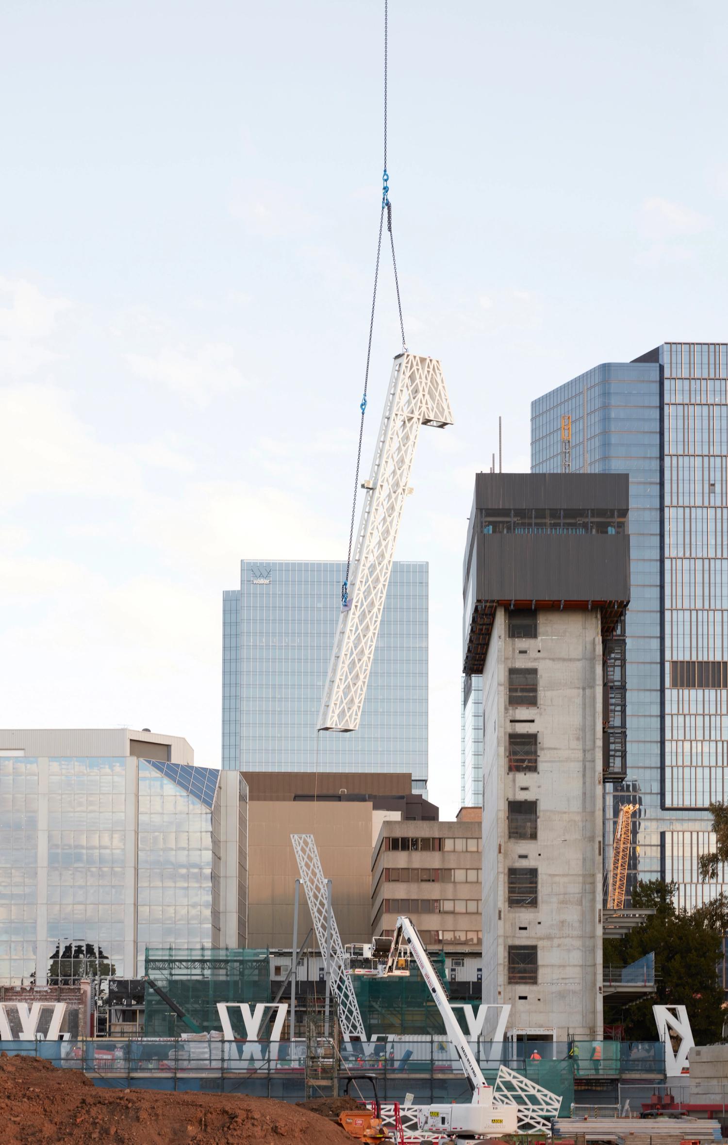 A white frame piece hanging from a cable above a construction site