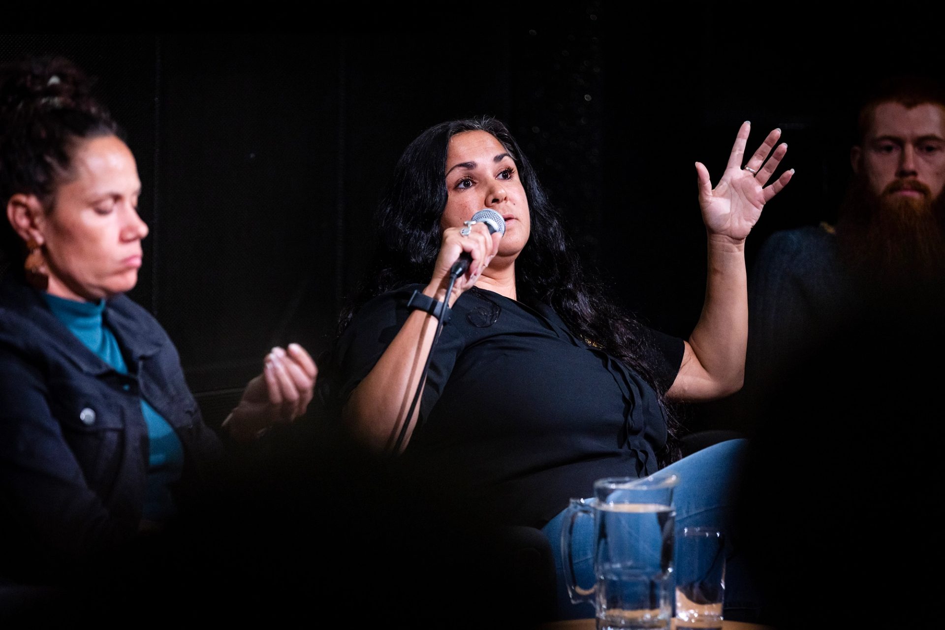 Woman talks with microphone to her mouth and arm raised