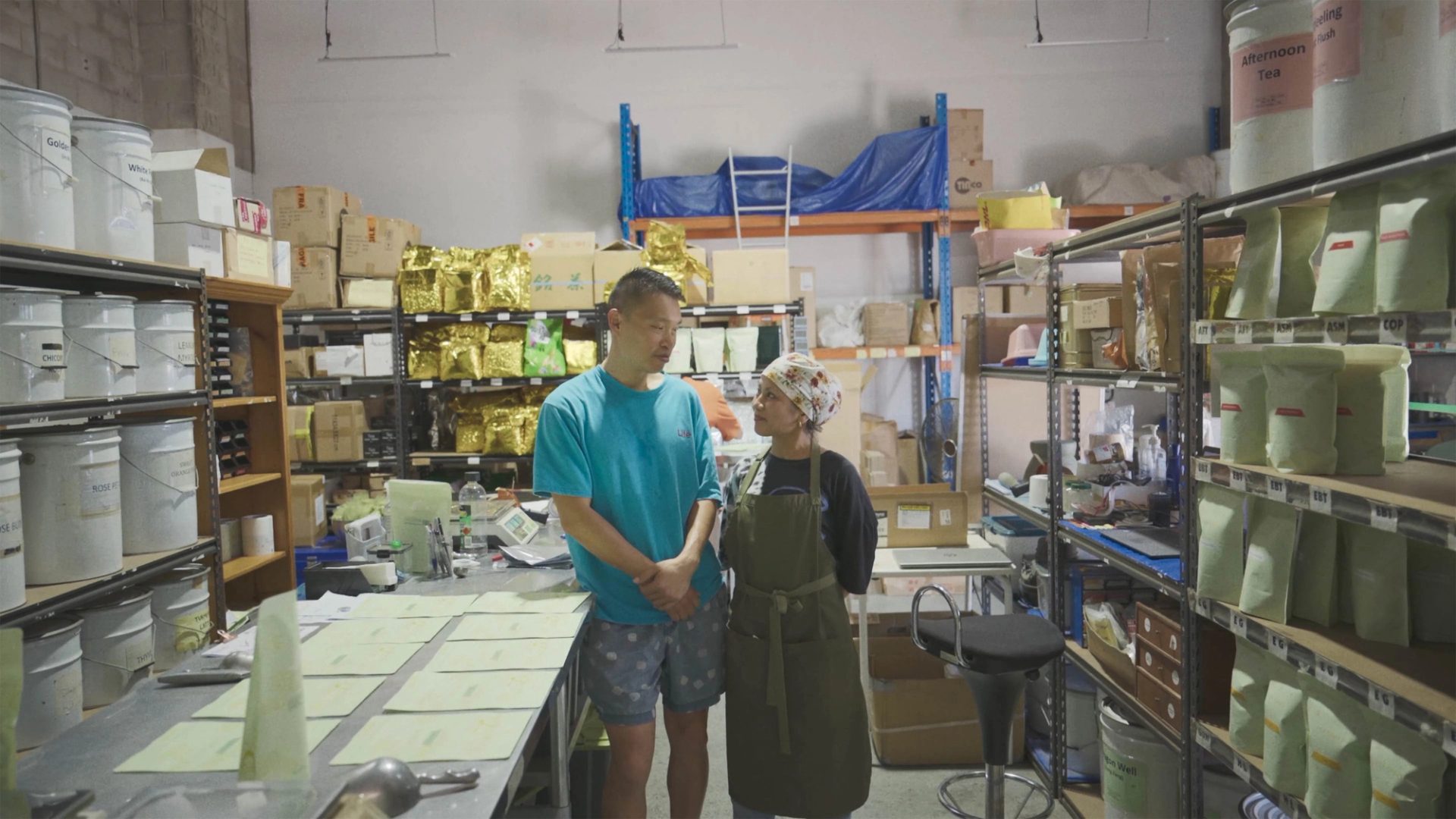Two people standing in the middle of a tea manufactuing factory.