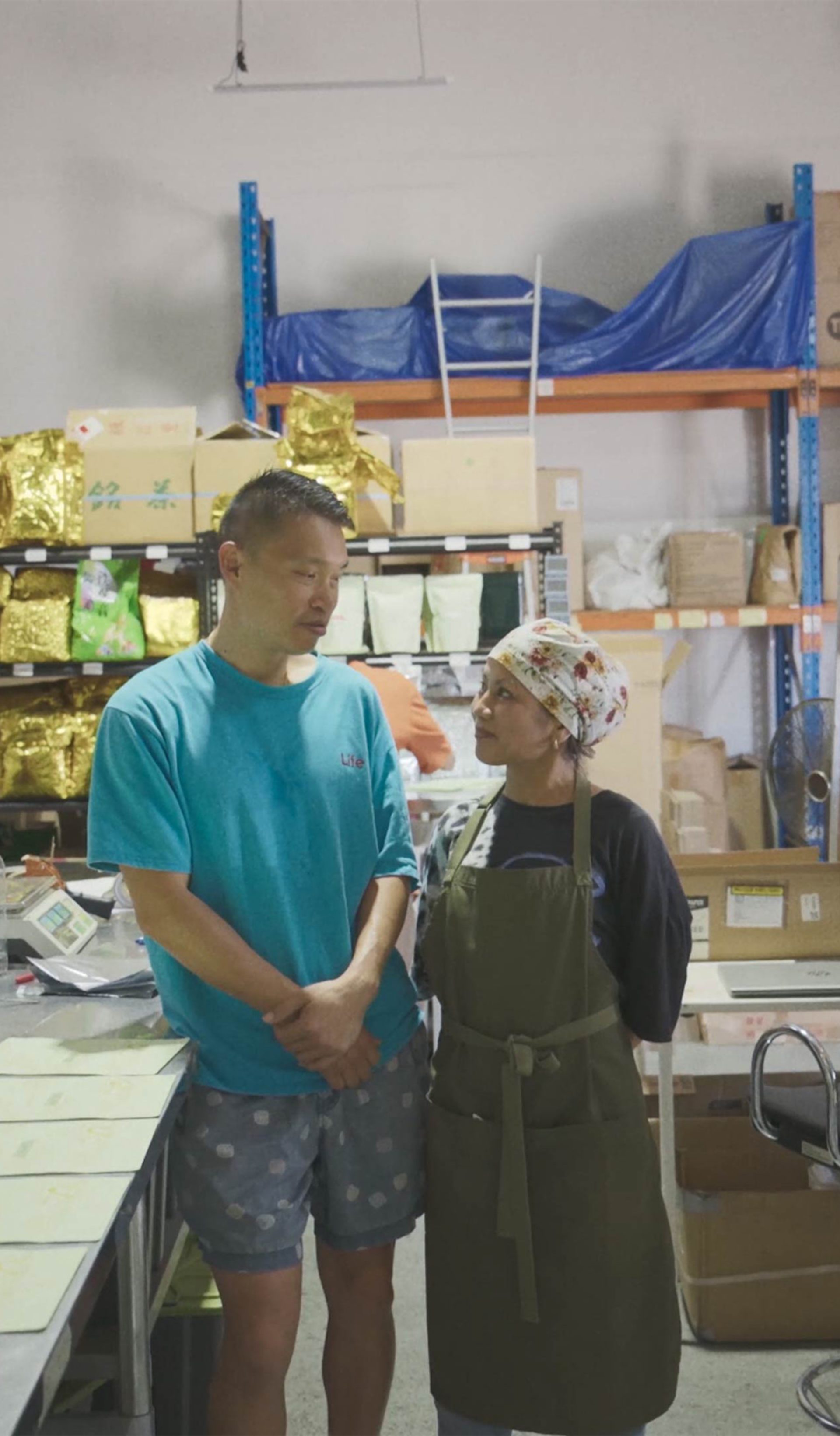 Two people standing in the middle of a tea manufactuing factory.