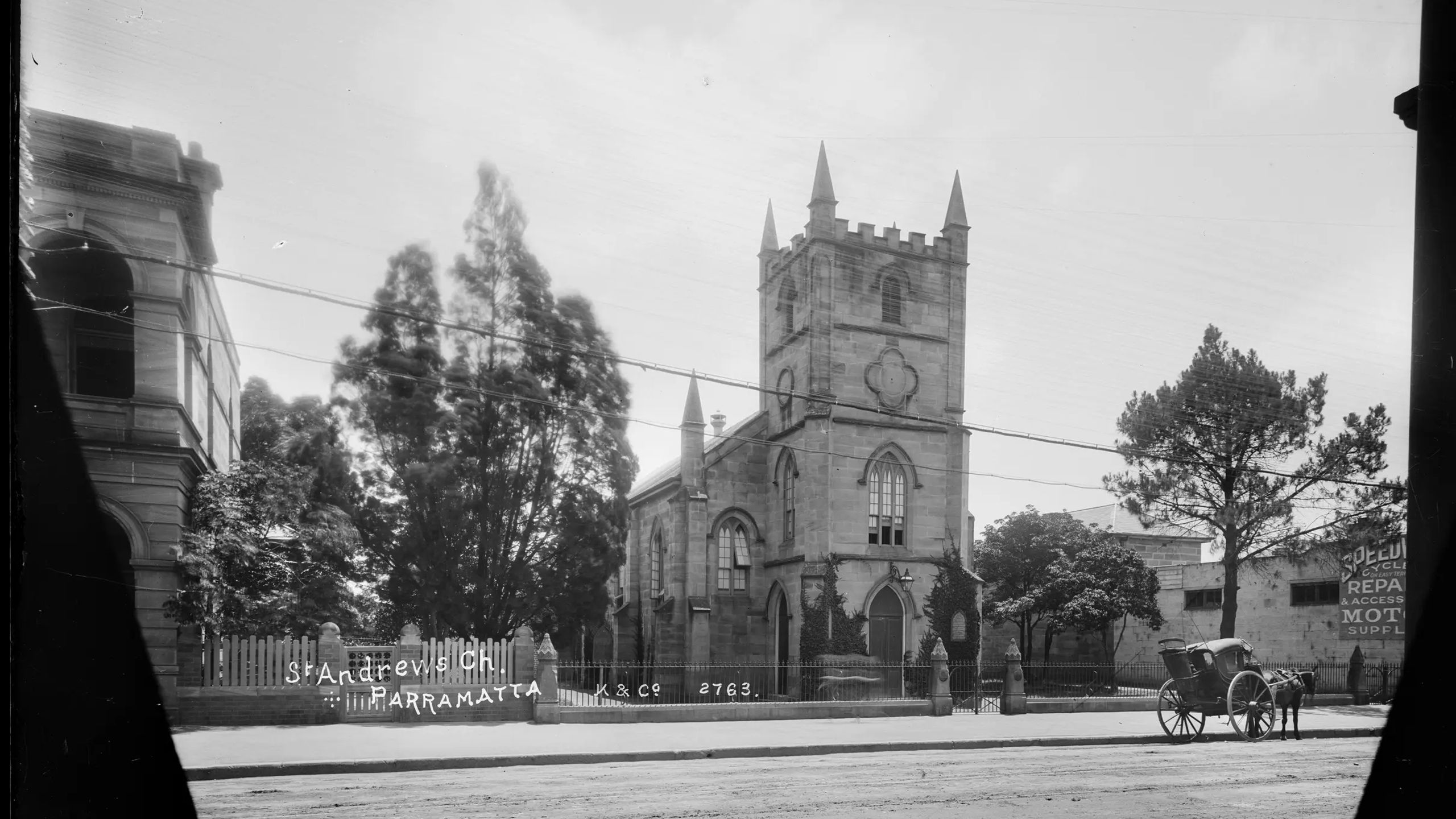 Silver gelatin dry plate glass negative in landscape format. The image depicts St Andrews Presbyterian Church in Parramatta. The church is depicted in the centre of the image. The front of the church features a turret like tower with four spires. The electric tramway is depicted in the foreground of the image. Other buildings are partially depicted on either side of the church. A hansom cab can be seen in the foreground in the left side of the image. The caption, studio mark and studio number are inscribed on the reverse of the negative.