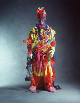 complex, fluroescent, multi-layered costume ensemble, predominantly in synthetic fibres, plastics and 'found objects'
