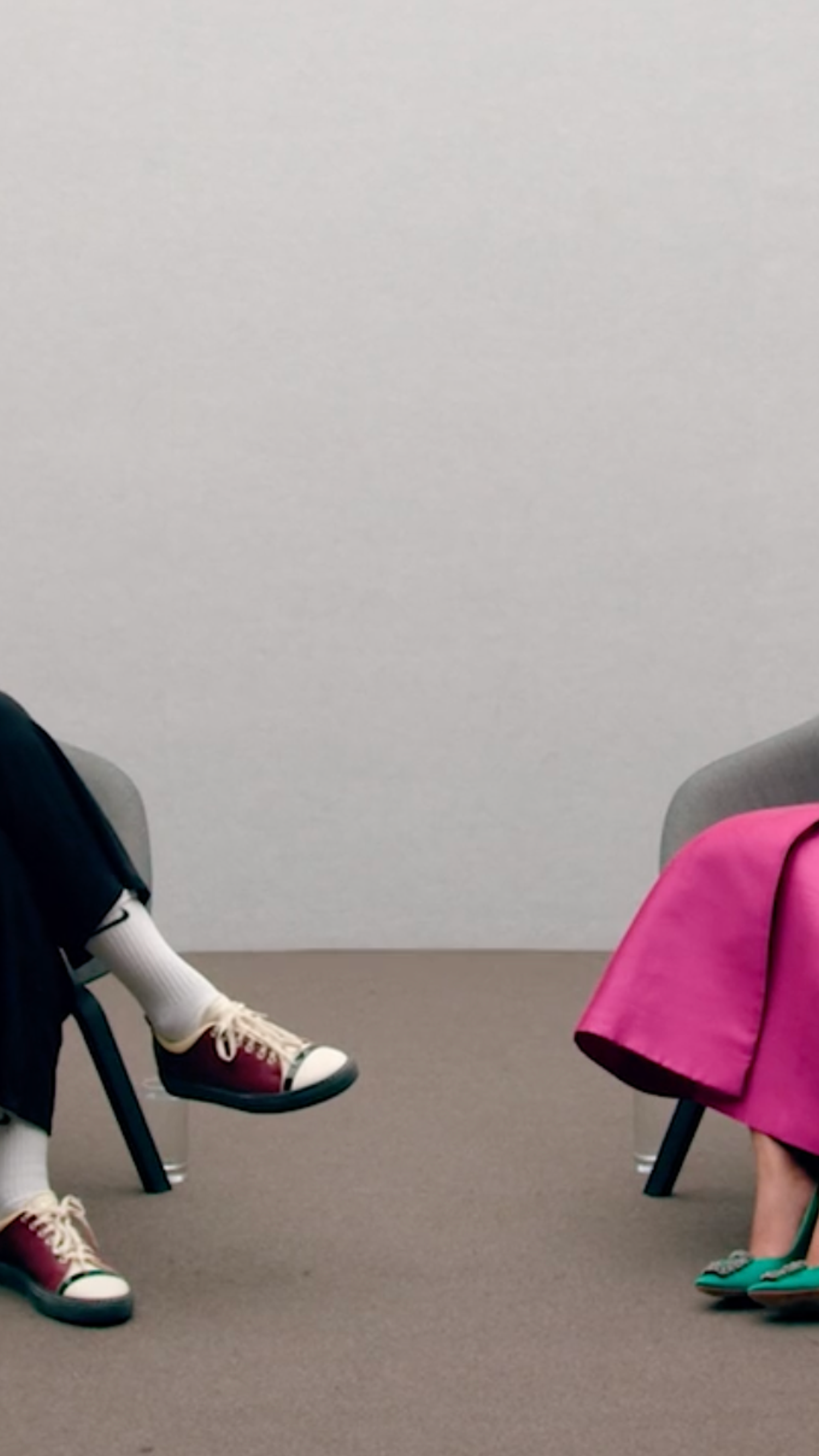 Two women sit on chairs talking to each other.