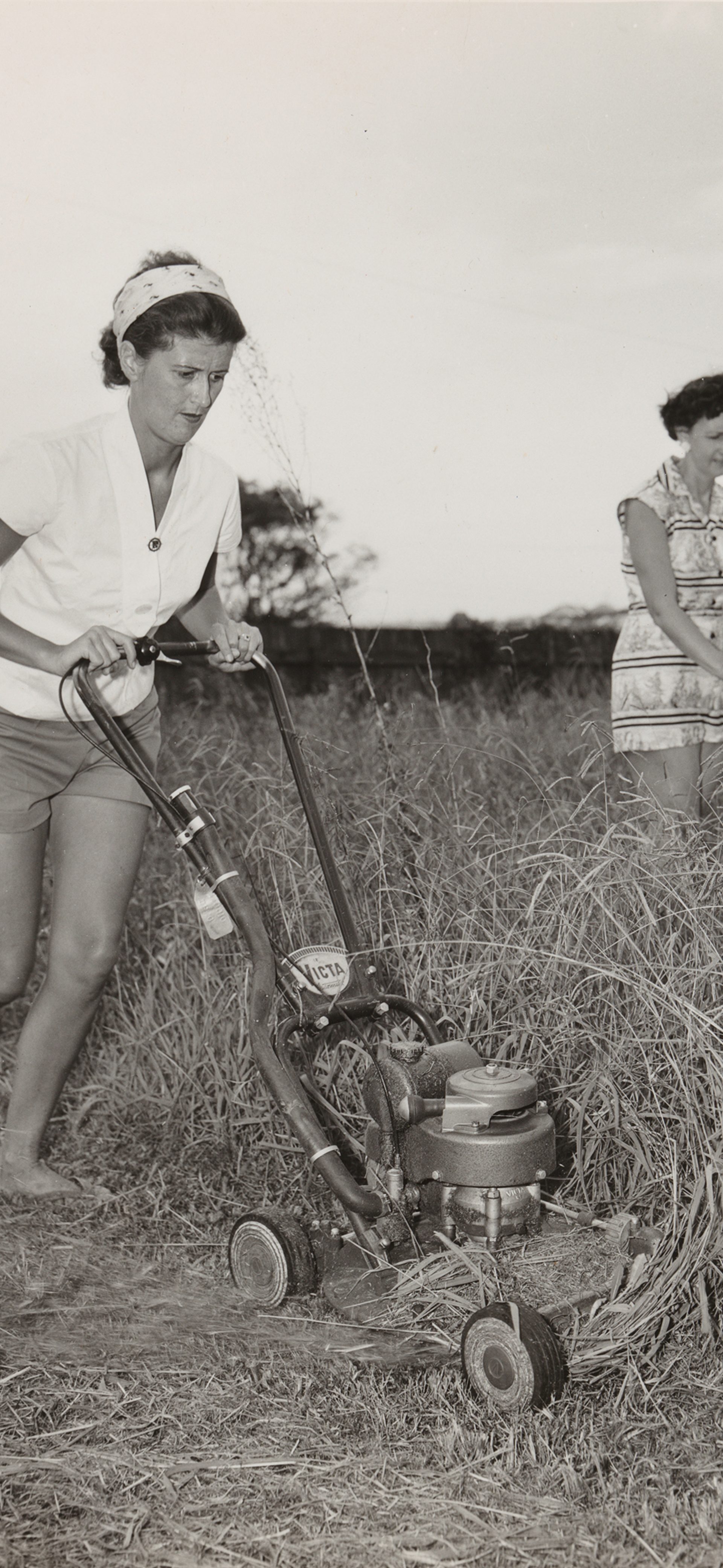 Two 1950s women mowing grass