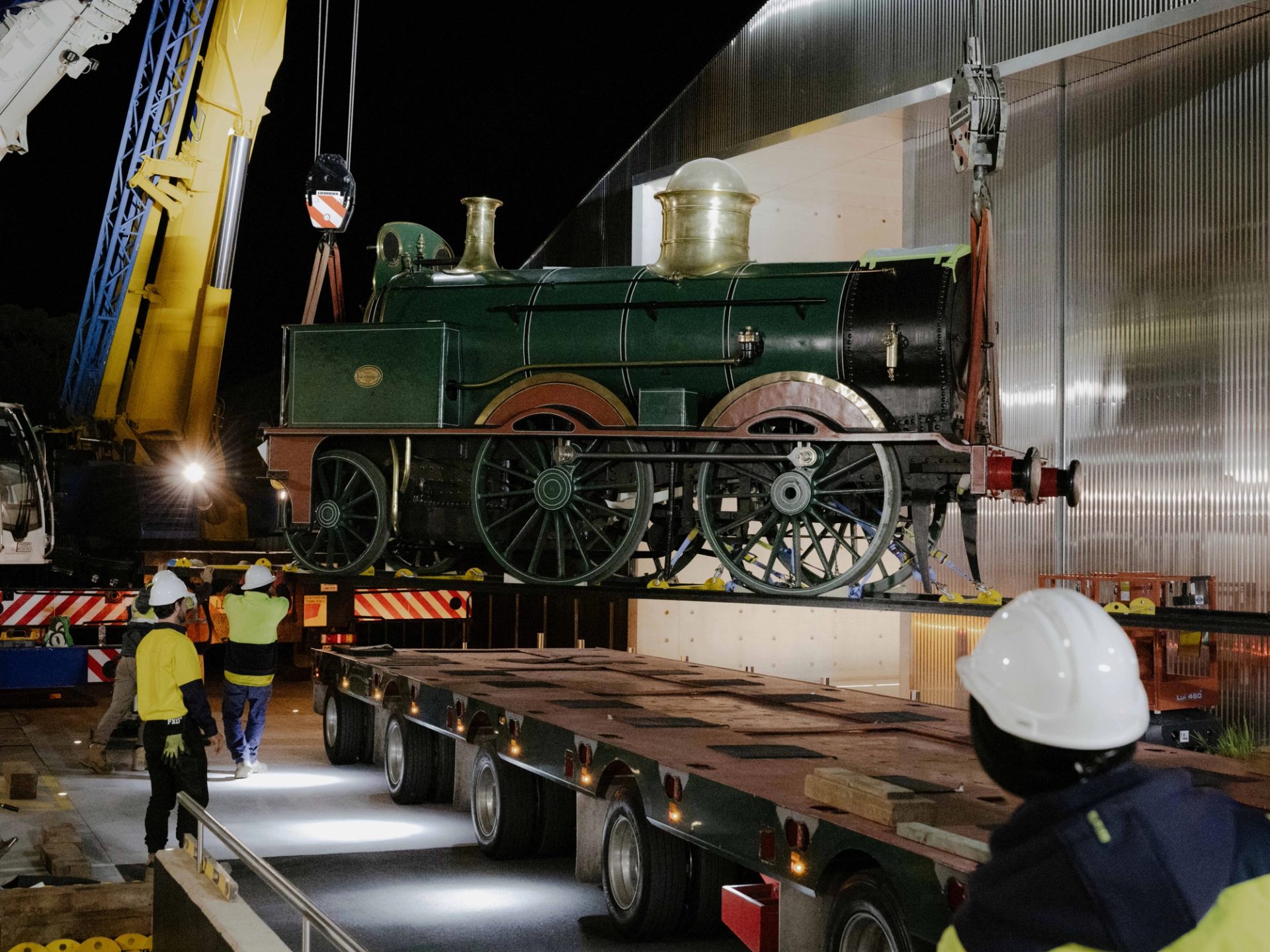 Train being lifted by cranes onto a truck.