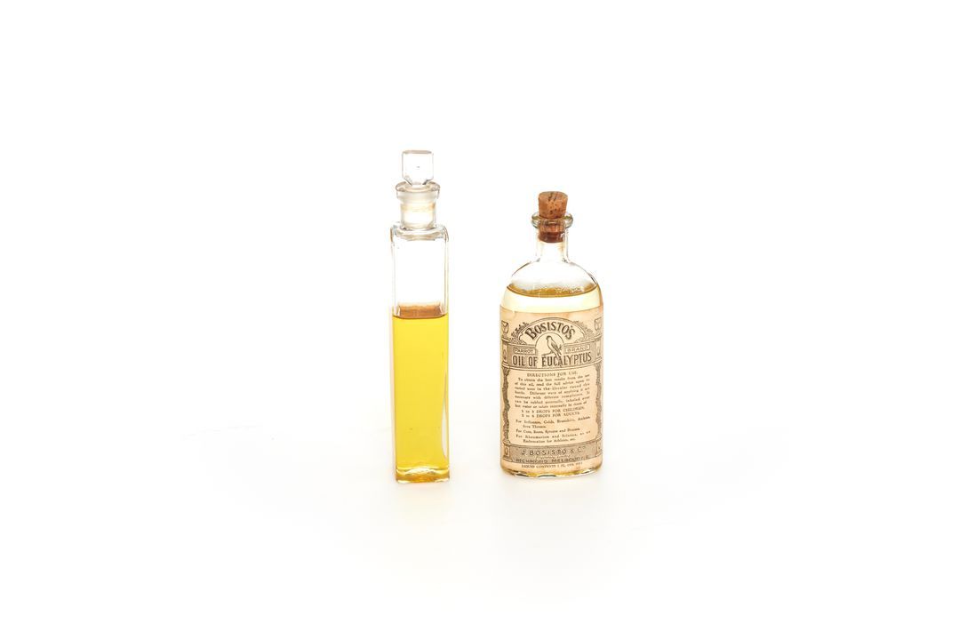 Two small glass bottles filled with eucalyptus oil. The bottle on the right has a label that reads ‘Bosisto’s Oil of Eucalyptus’