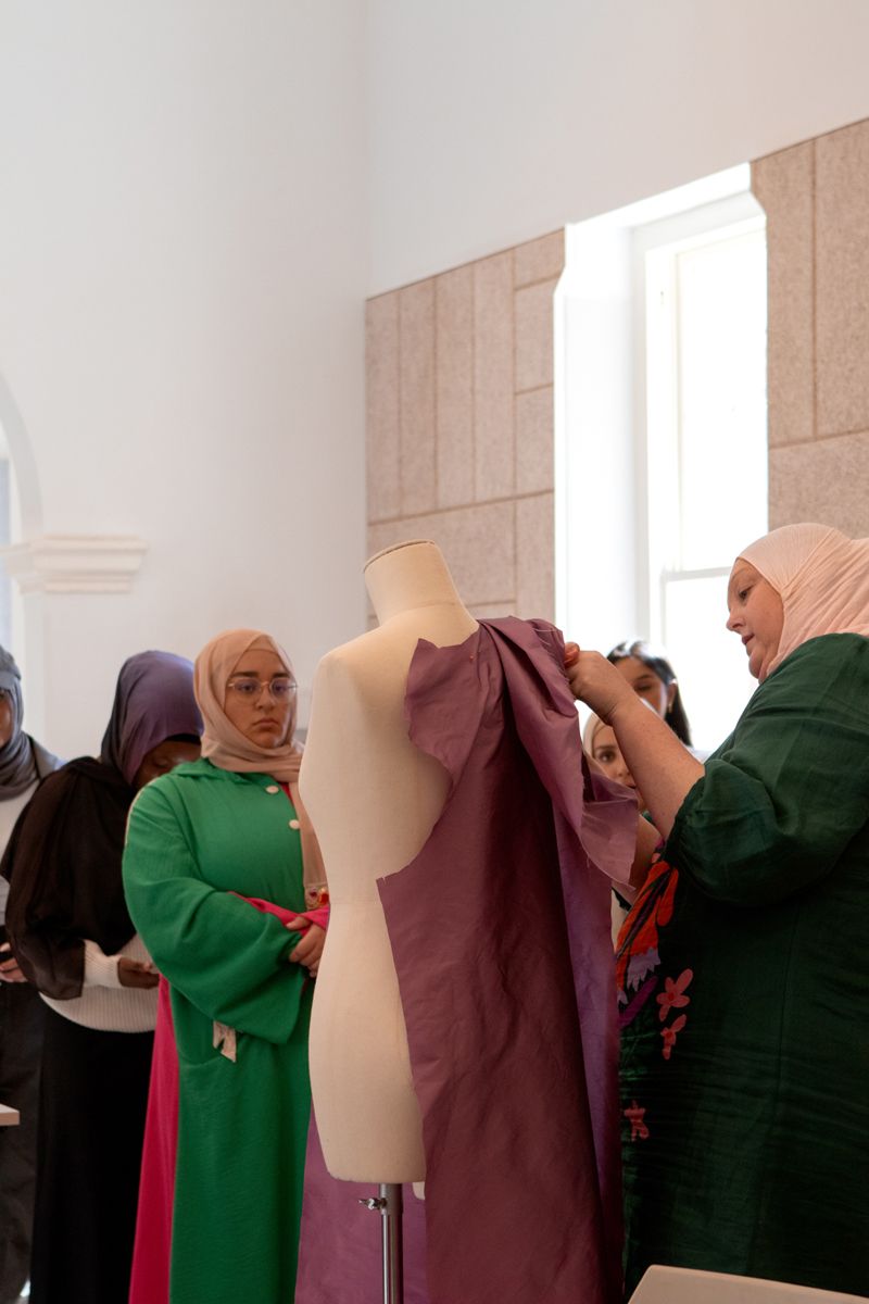 Figures working around a mannequin with fabric