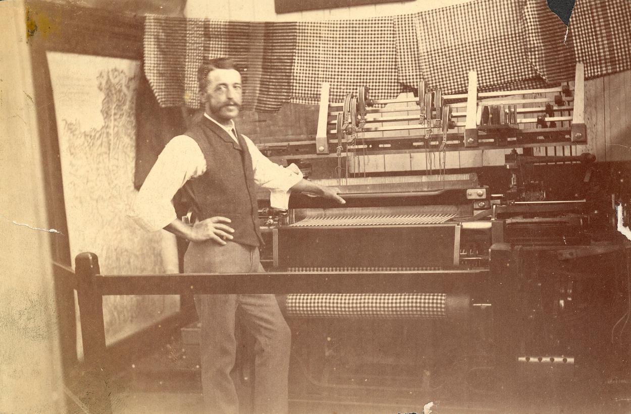 Sepia photograph of a man demonstrating a loom in public