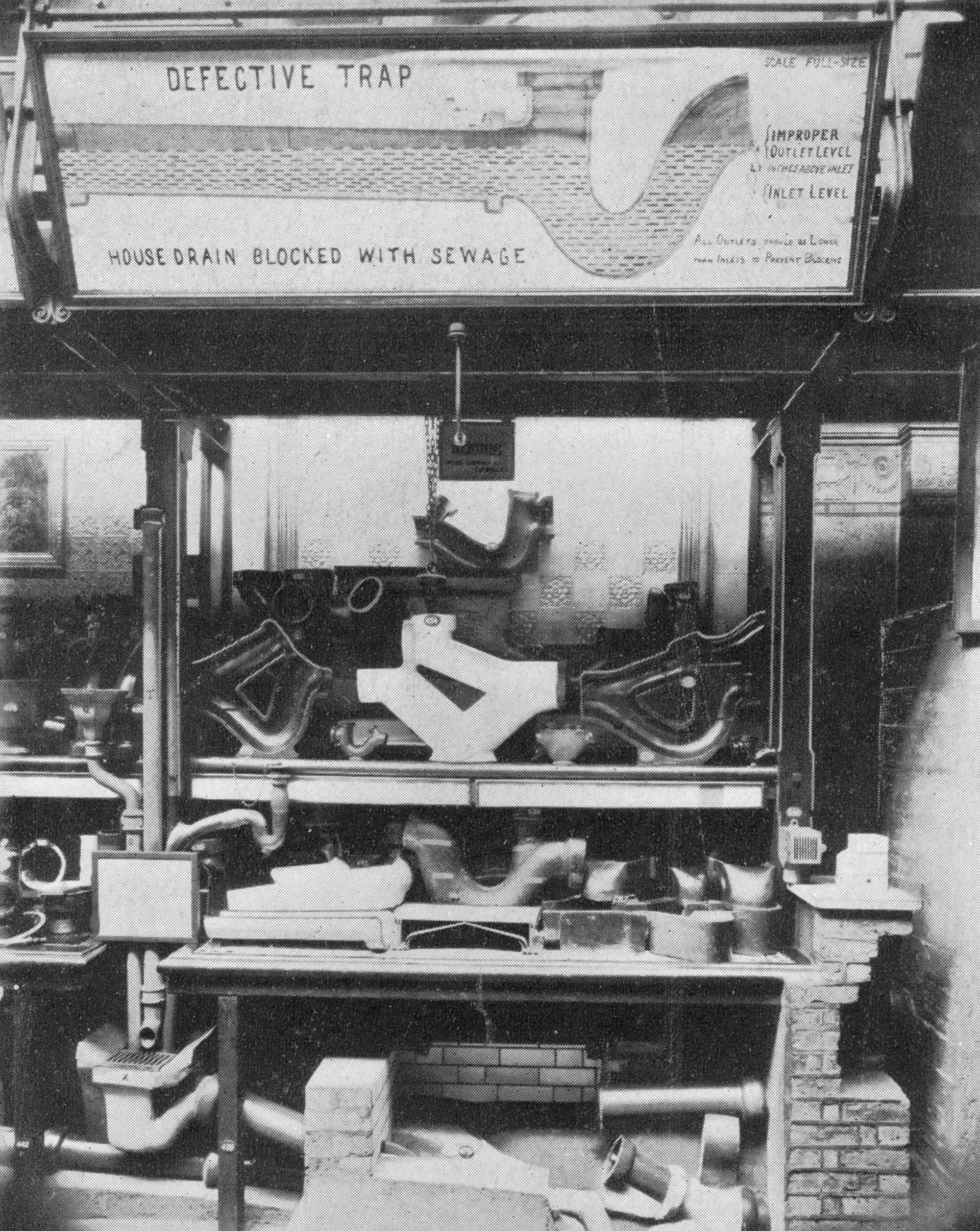 Black and white photograph of sanitation museum display with drainage pipes
