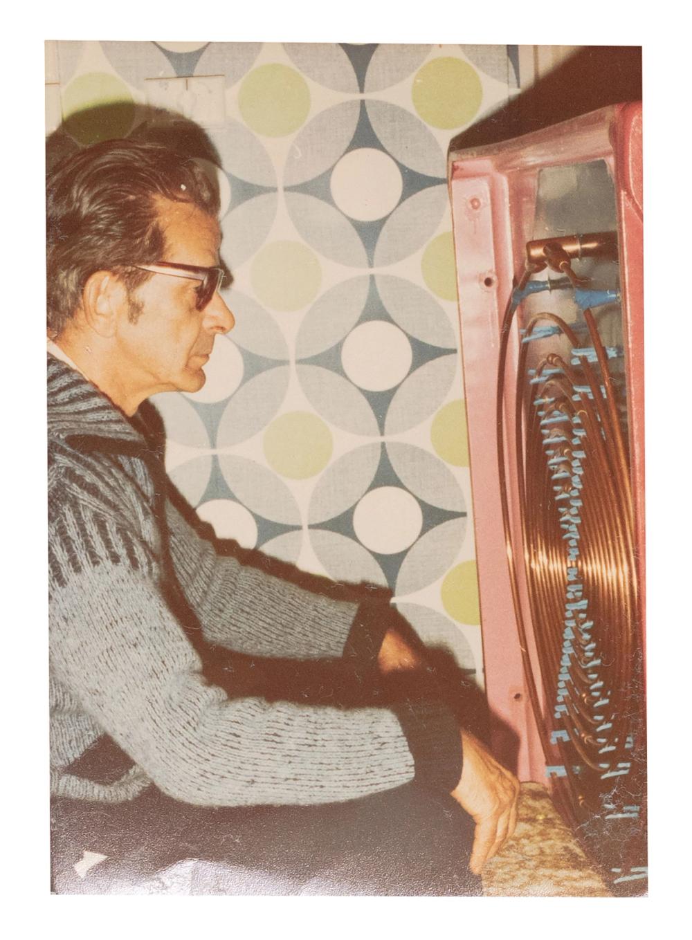 A man sitting in front of a oscillator machine and looking at it.