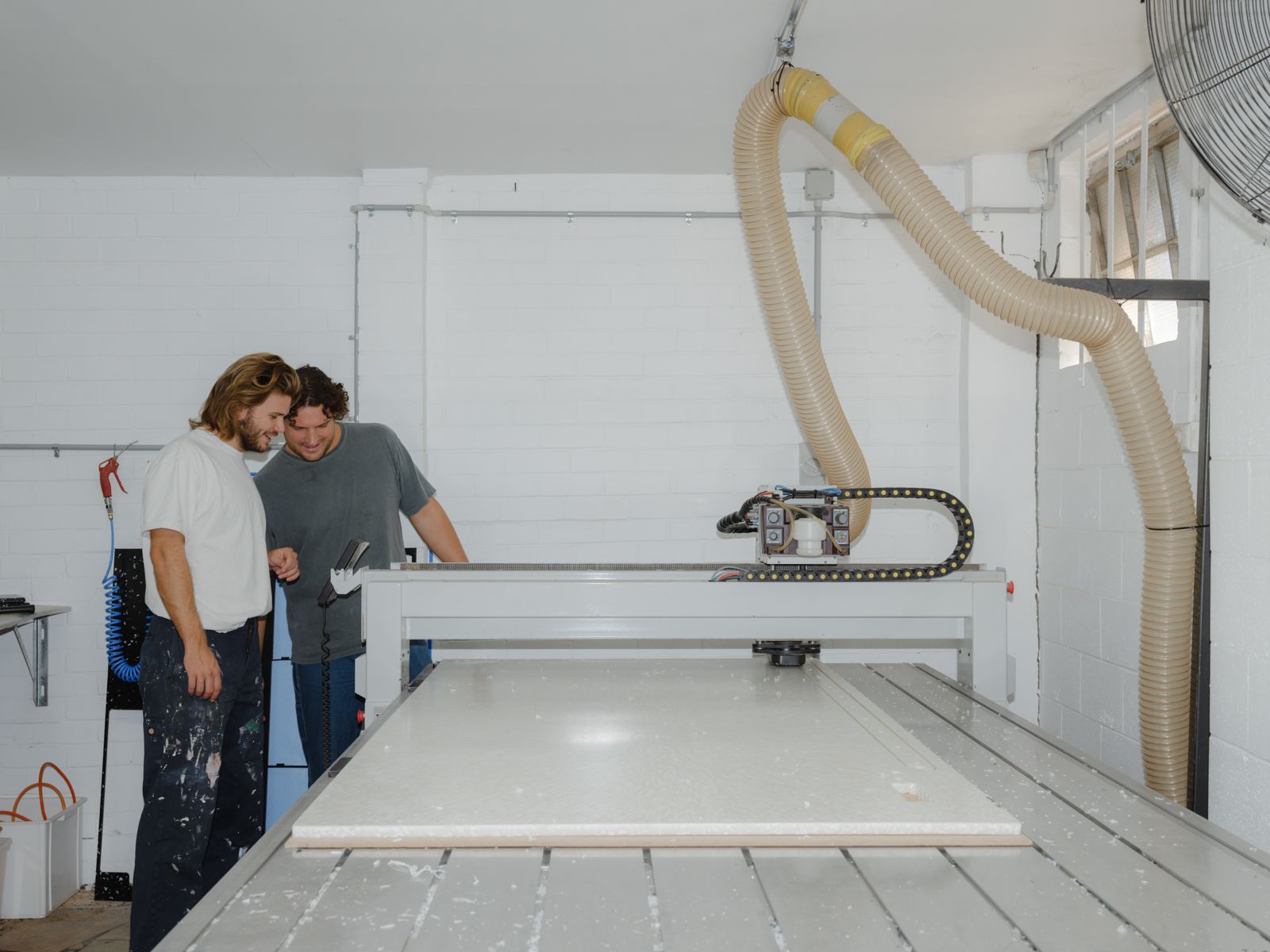Two figures looking at the cutting of a large piece of plastic.