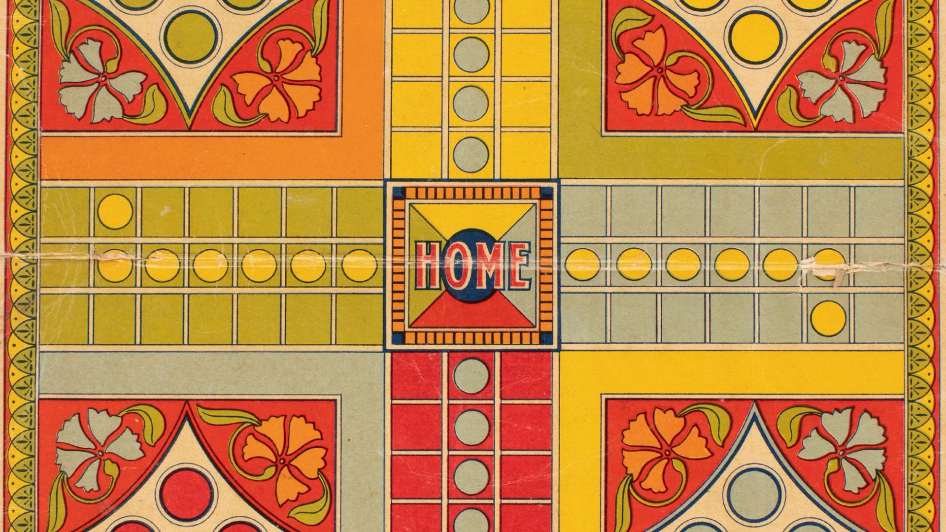 Close-up photograph of a red, yellow and green Ludo game board made of cardboard.
