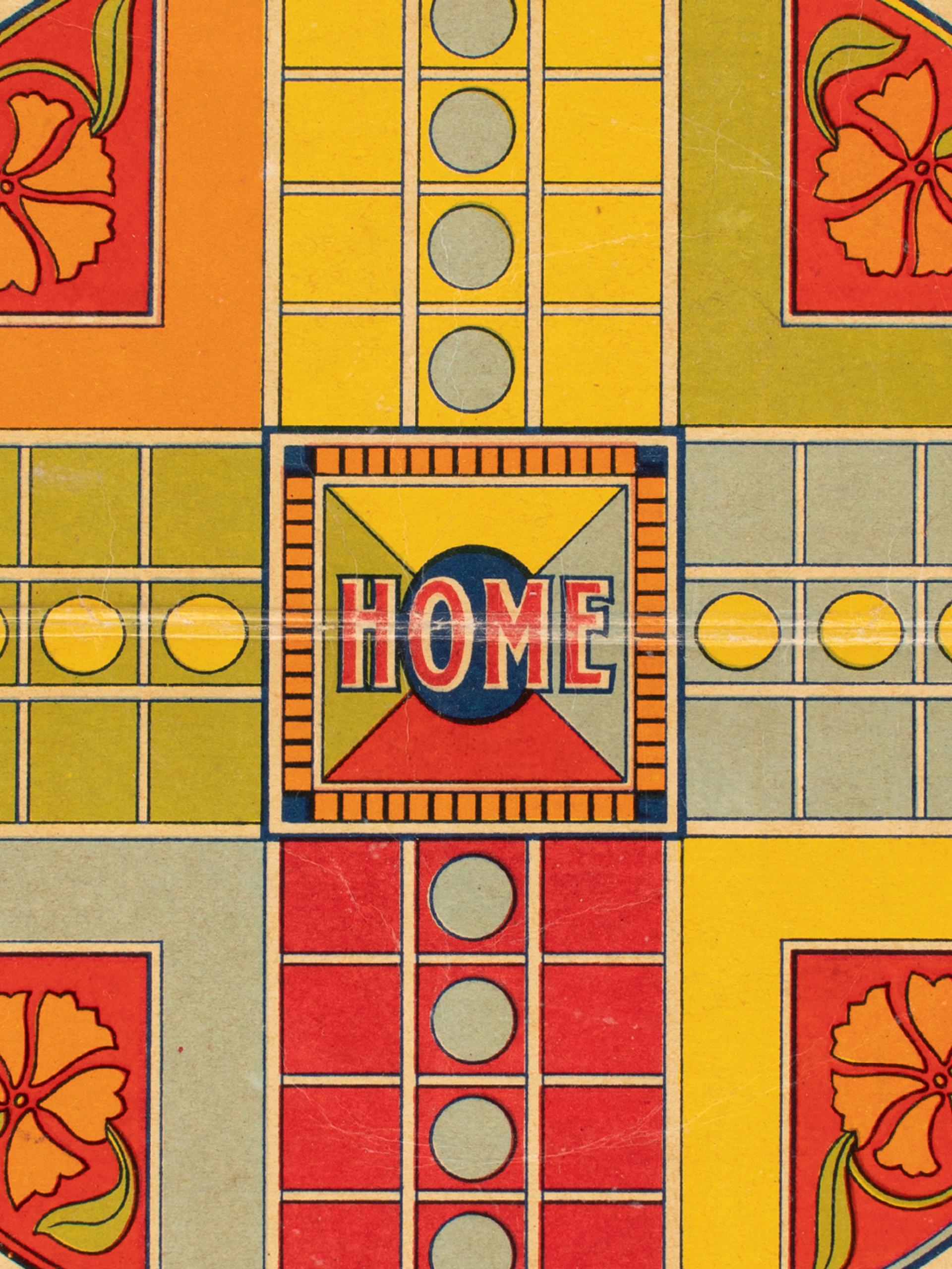 Close-up photograph of a red, yellow and green Ludo game board made of cardboard.