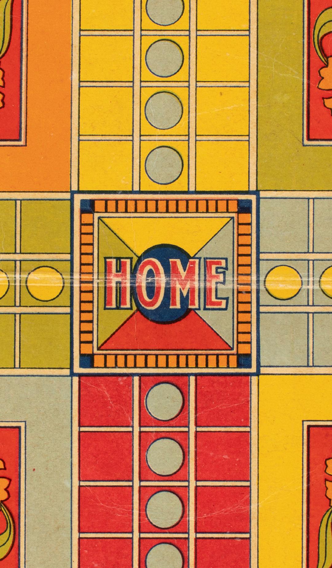 Close-up photograph of a red, yellow and green Ludo game board made of cardboard.