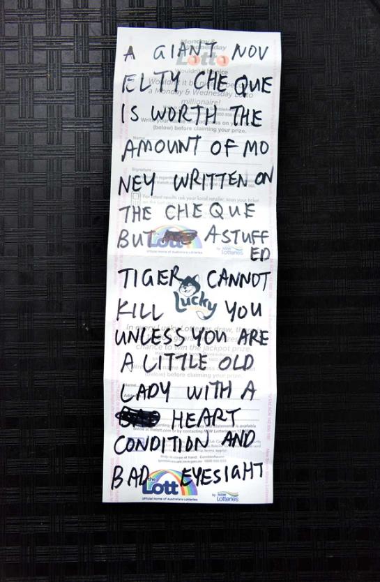Note reading “A GIANT NOVELTY CHEQUE IS WORTH THE AMOUNT OF MONEY WRITTEN ON THE CHEQUE BUT A STUFFED TIGER CANNOT KILL YOU UNLESS YOU ARE A LITTLE OLD LADY WITH A HEART CONDITION AND BAD EYESIGHT