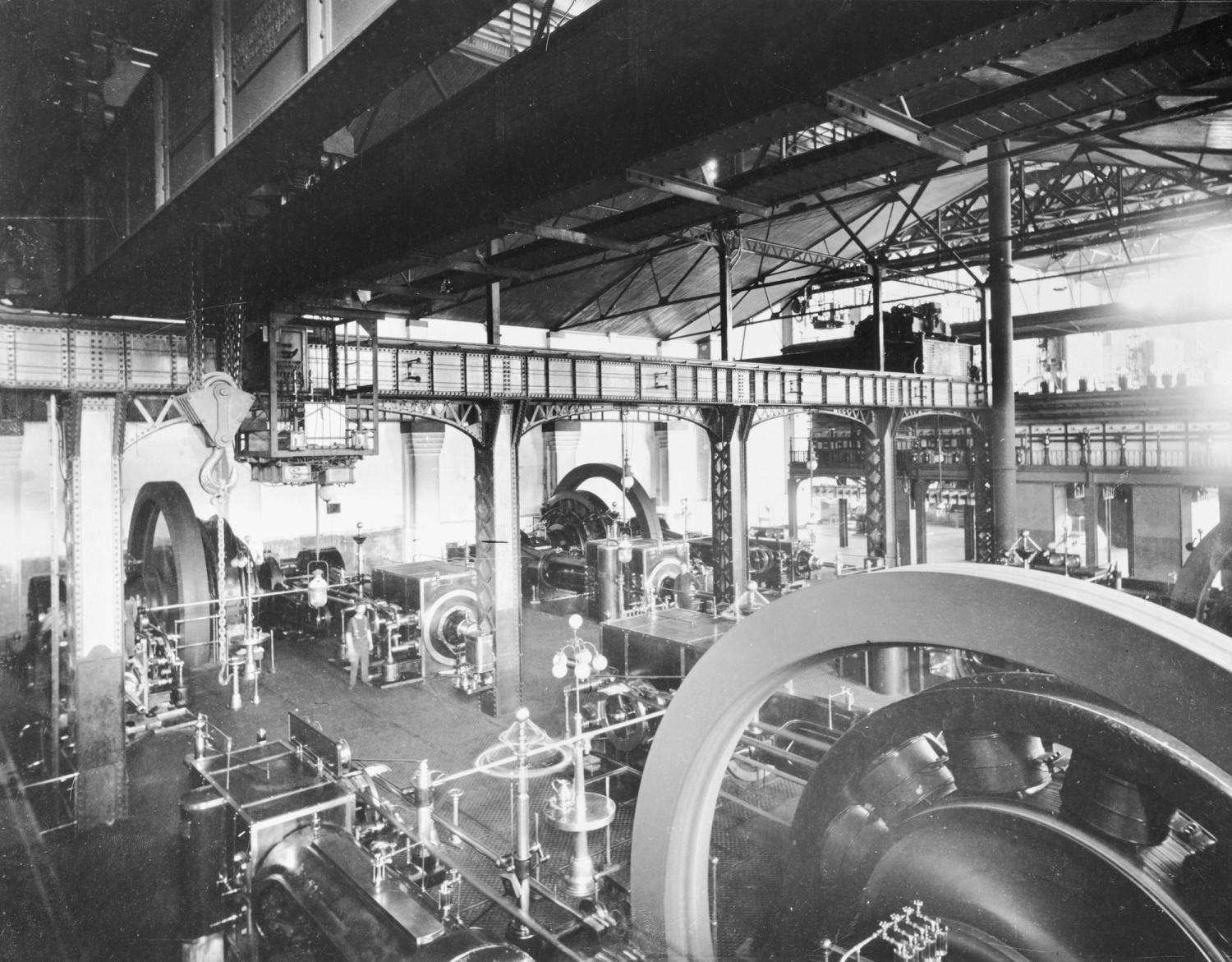 Black and white archival image of the Power House with machinery whirling and gantry system
