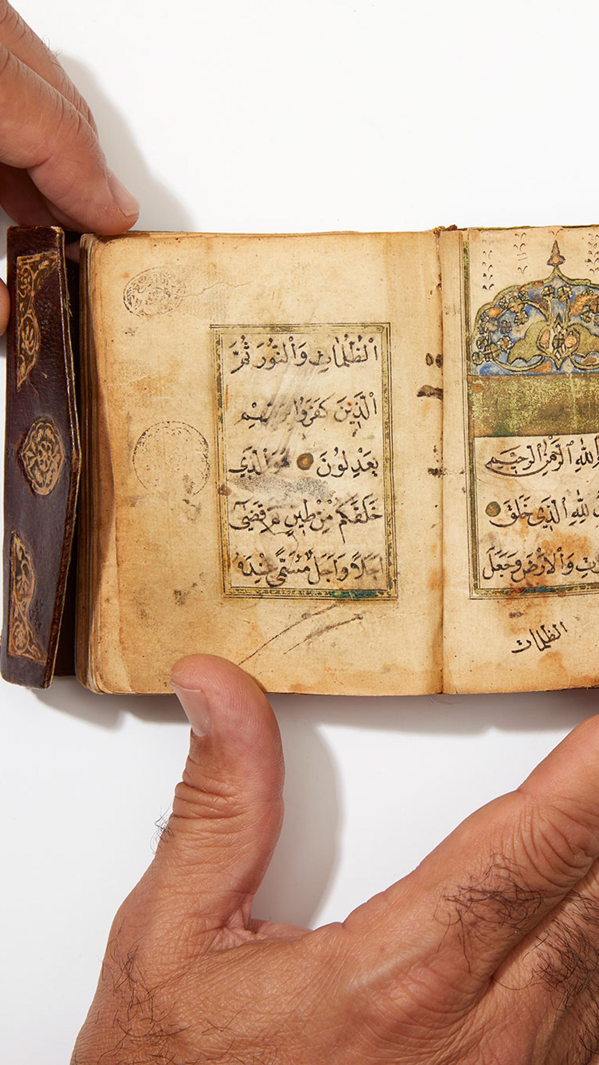 Photograph of Quran with two hands on page