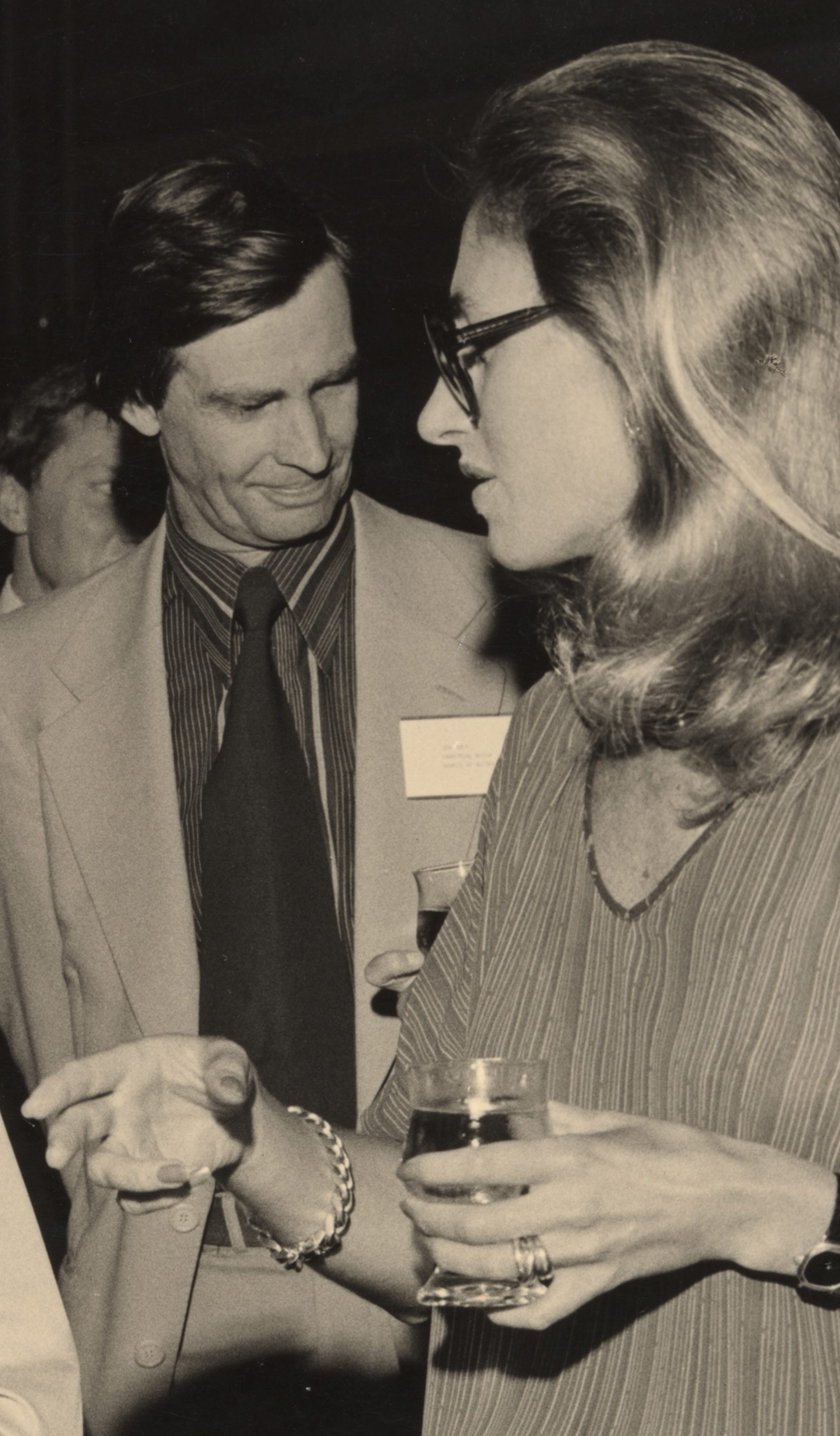 A sepia-toned photograph of the design awards, in which four figures -- two men, two women -- speak together in a loose huddle, drinks in hand.
